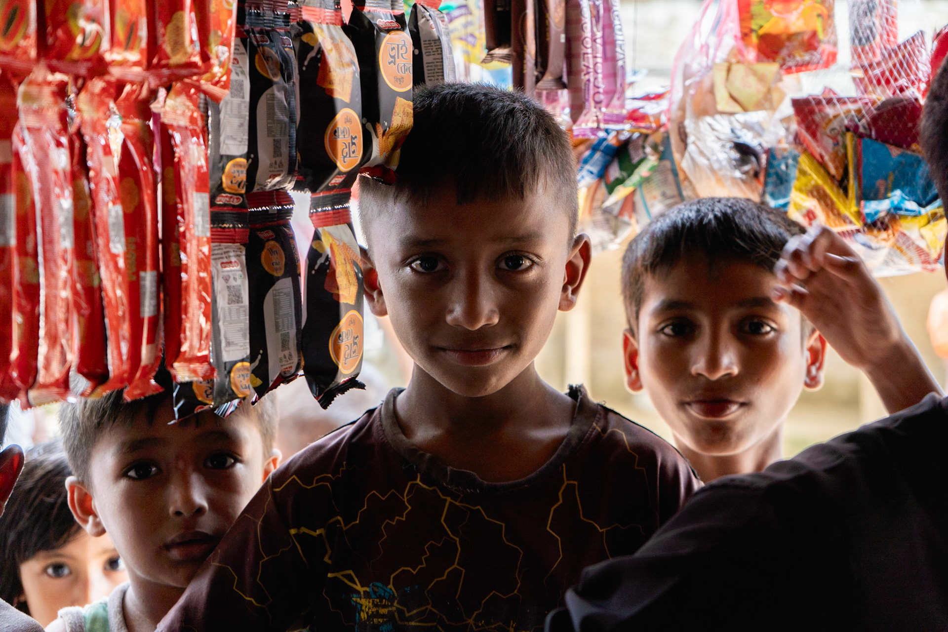 Three boys stand at one of the many street stalls in the Rohingya refugee camps