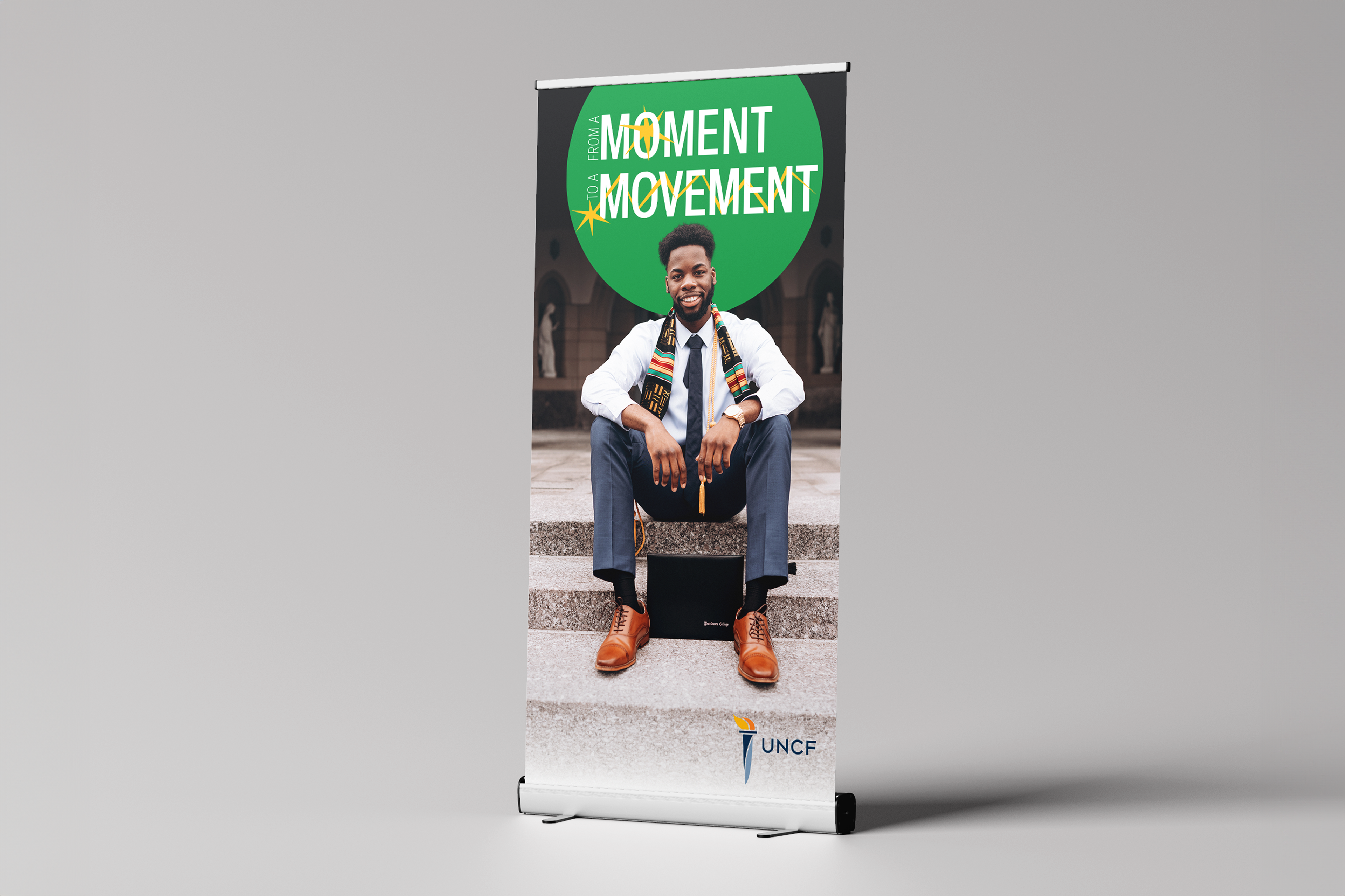 A mockup of a pull-up banner for the UNCF campaign with an image of a Black graduate and the campaign slogan
