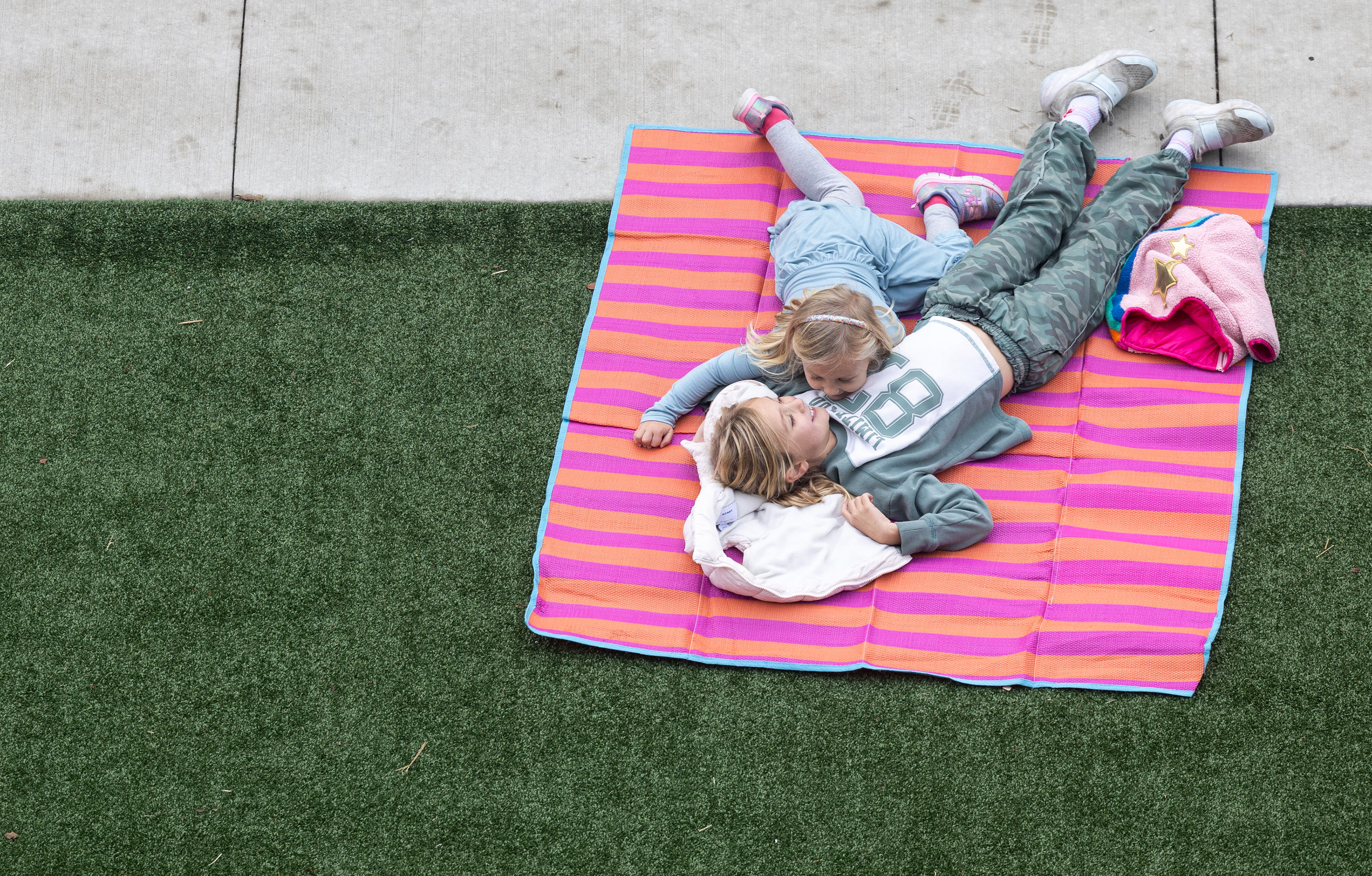 Baylor Brown, 4, lays with her sister Emmy Brown, 8, on Saturday, Nov. 8, 2025, before the Veteran’s Parade in downtown Bowling Green, Ky. The sisters were among a large part of the community that attended the parade. 