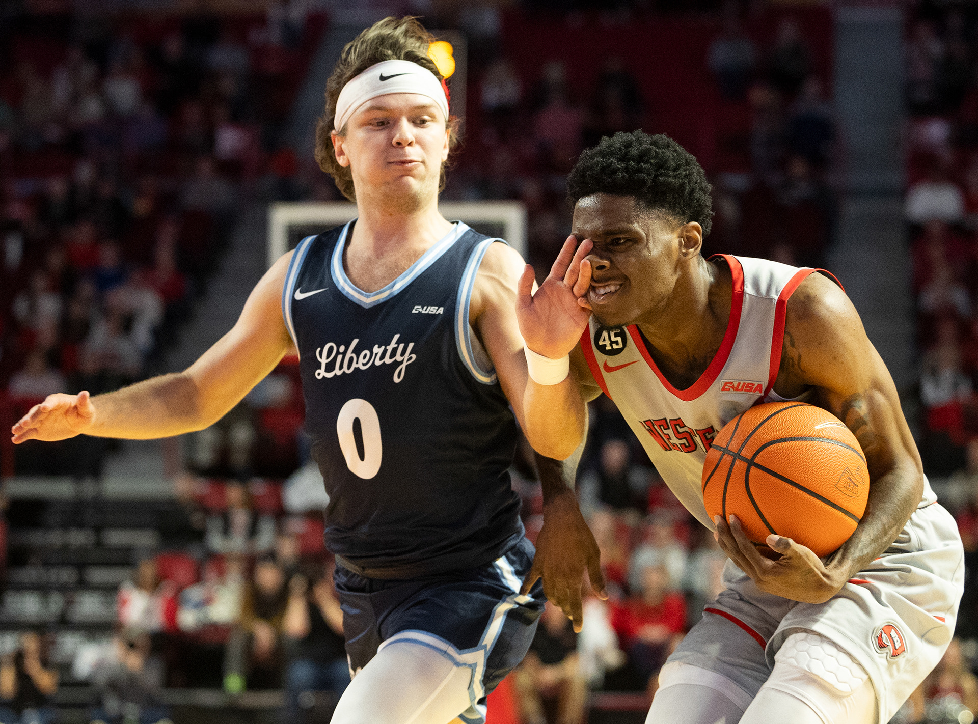Liberty Flames guard Colin Porter (0) pokes Western Kentucky Hilltoppers guard Don McHenry (2) during McHenry’s drive to the goal during the Western Kentucky Hilltoppers’ final home game in E.A Diddle Arena in Bowling Green, Ky., on Saturday, March 8, 2025.