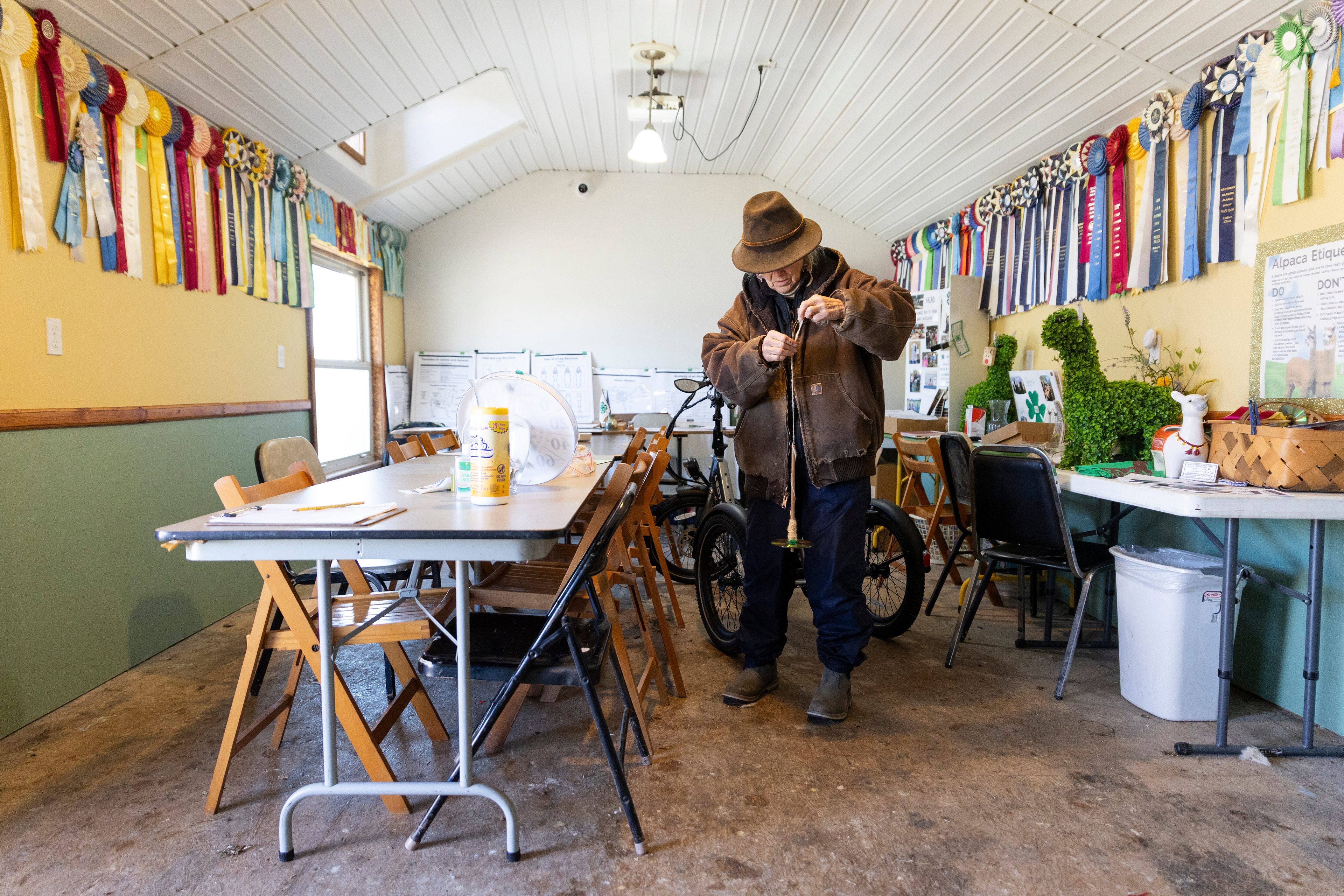 Alpaca farmer Elaine Painter winds alpaca fur around her homemade drop spindle in her farm house on Feb. 23, 2025. “This is a modern-day drop spindle, because I made it out of a CD,” Painter said. “This is one I’ve used to teach people the art of spinning.” Painter has worked as an alpaca farmer for over 30 years, and has collected numerous awards for her alpacas. Painter also holds summer teaching clinics for children in her farm store.