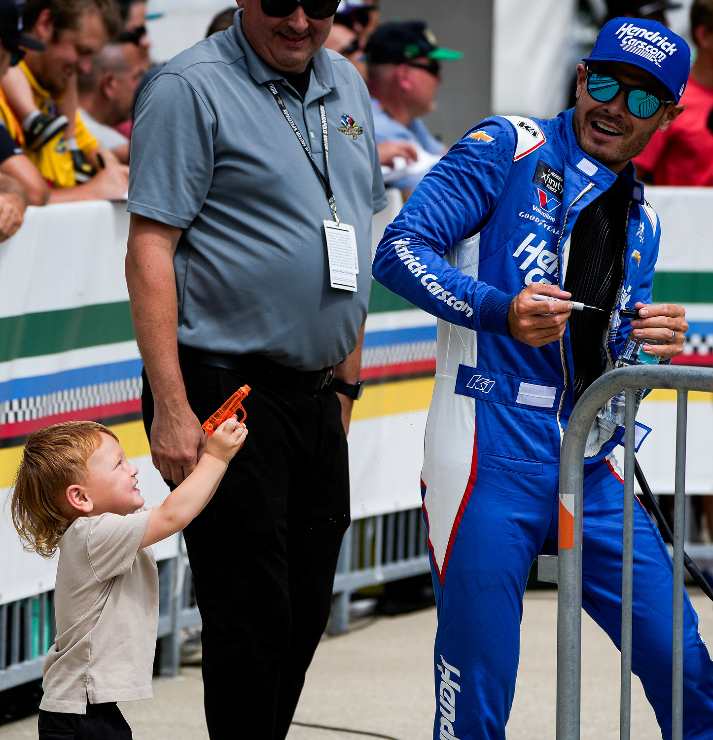 Kyle Larson is shot by his son with a water gun after Larson finishes signing autographs on Saturday, July 26, 2025, before the Pennzoil 250 at Indianapolis Motor Speedway.