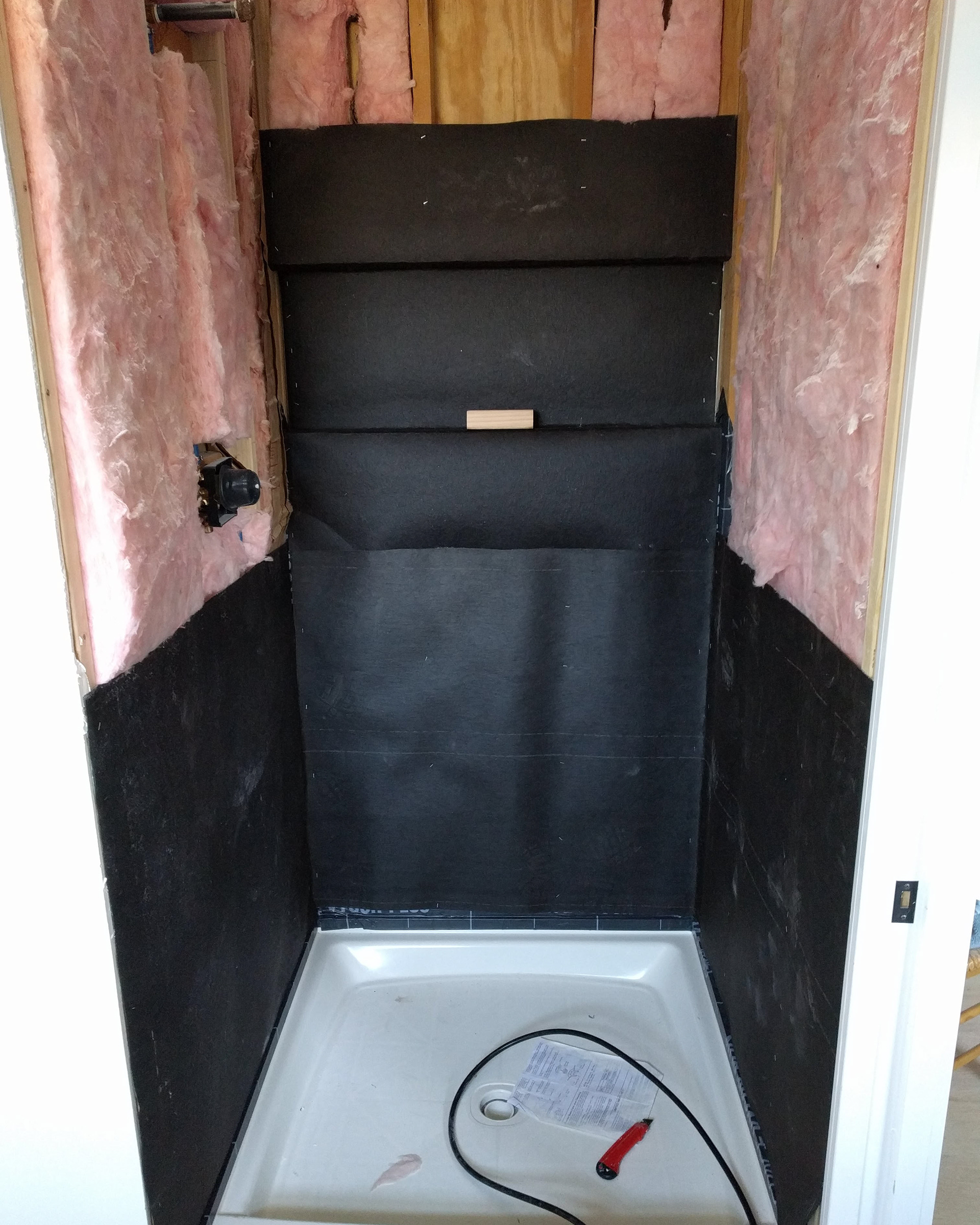 Installing insulation and tarpaper for shower.