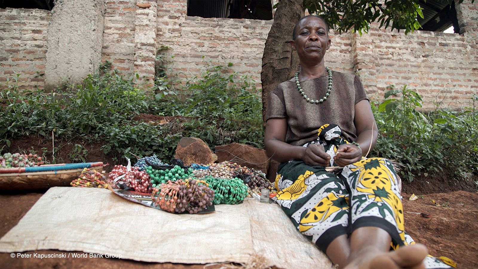 Esther Atieno sits alongside beadwork she’s made in Kisumu, Kenya. She recently purchased a jiko kisasa (firewood stove), which uses less fuel than her previous stove. By not having to buy firewood as often, she can concentrate on activities that earn her extra income. Photo: Peter Kapuscinski / World Bank