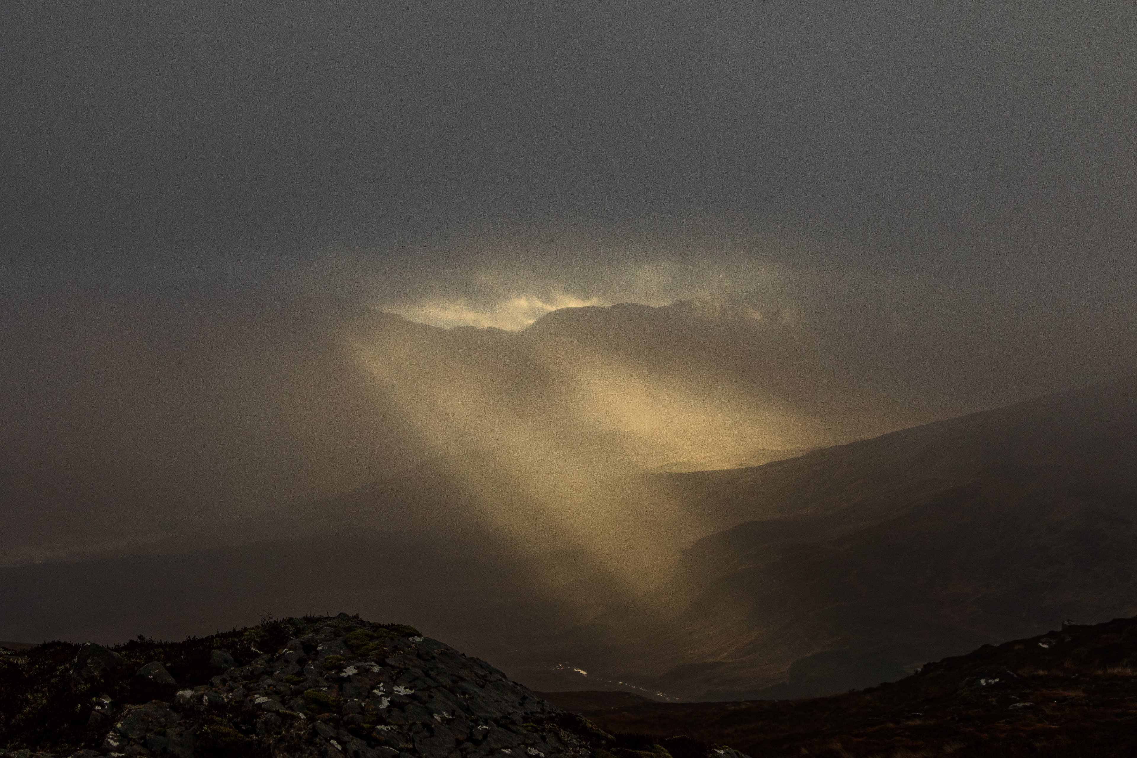Shafts of sunlight pushing through heavy cloud in Glen Lyon, Scotland