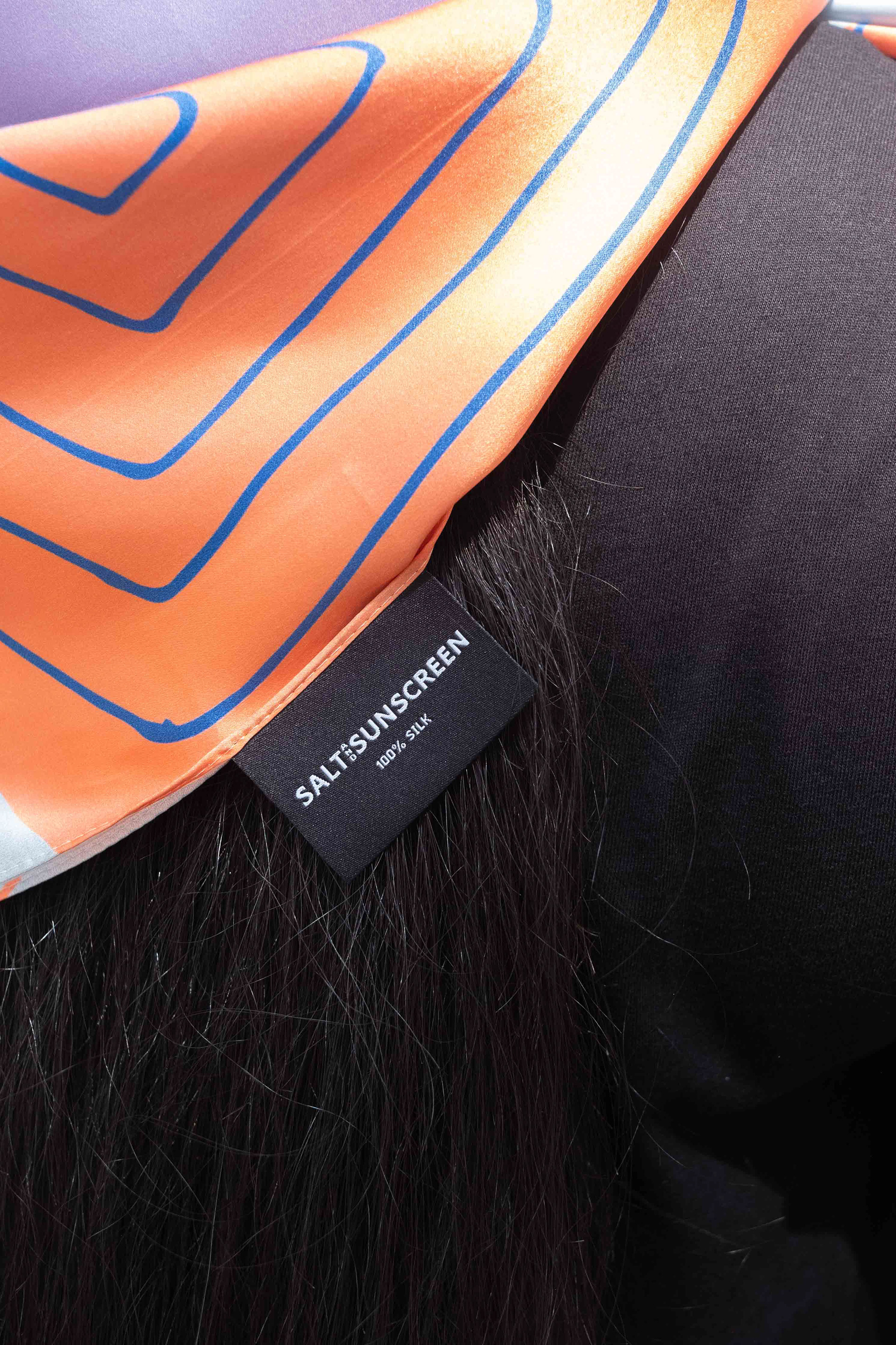 close up of the printed silk scarf with the brand label