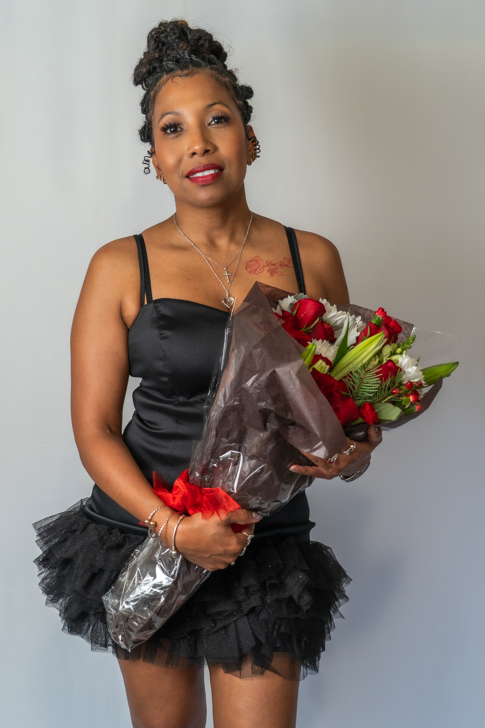 Woman holding bouquet, posing for birthday shoot in studio.