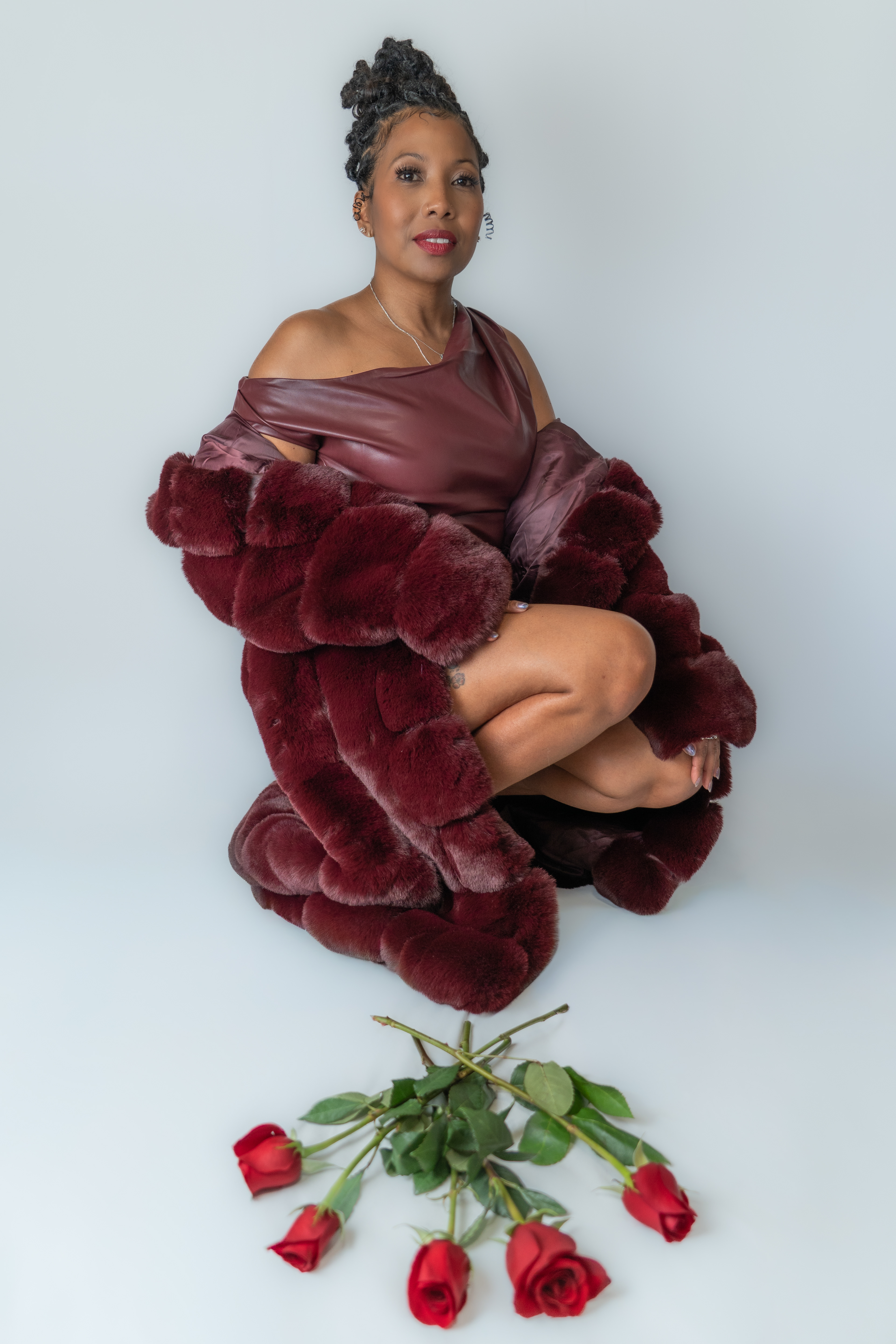 Woman posing for birthday shoot in studio, roses in the foreground.