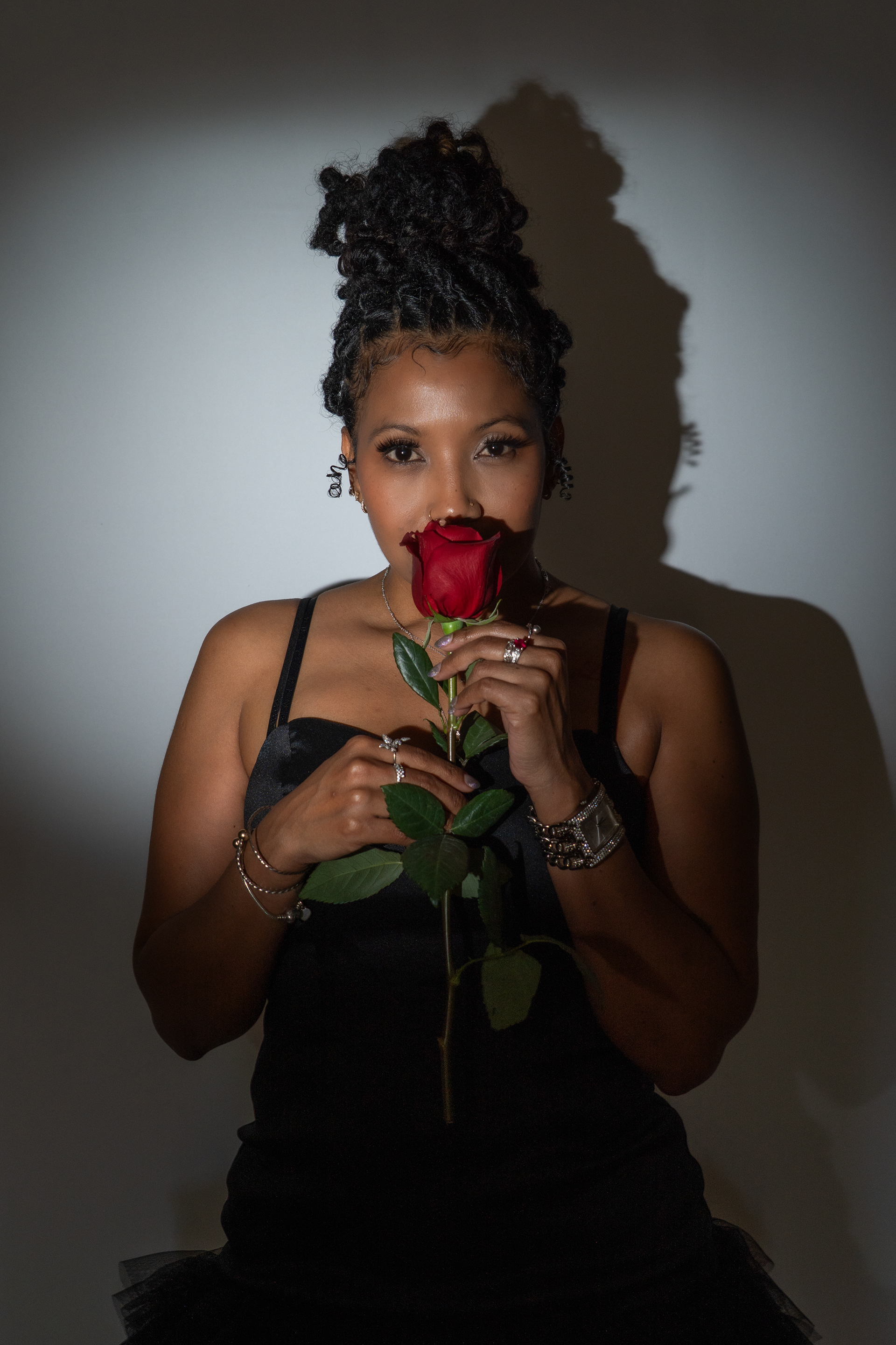 Woman smelling rose, posing for birthday shoot in studio.