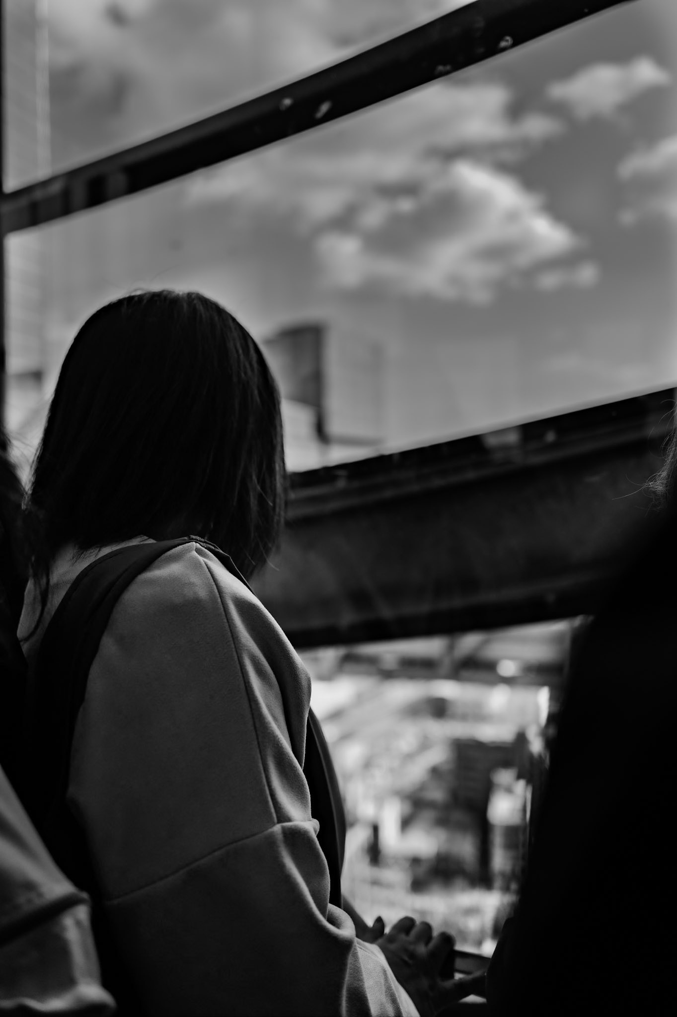 A young woman stands in the elevator back turned, looking out at the city below.
