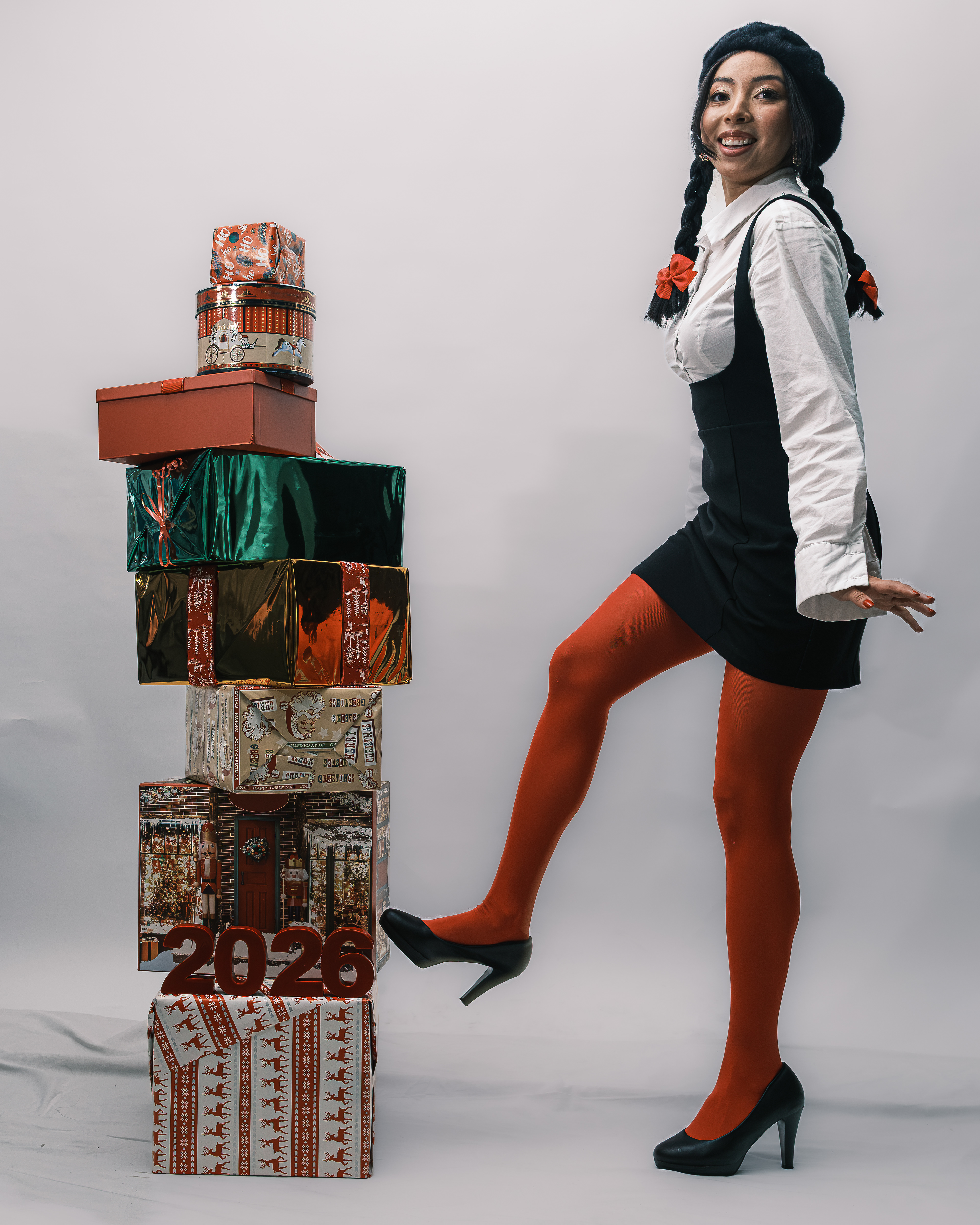 Mujer con una pierna levantada junto a una torre de regalos navideños y cifras de 2026.