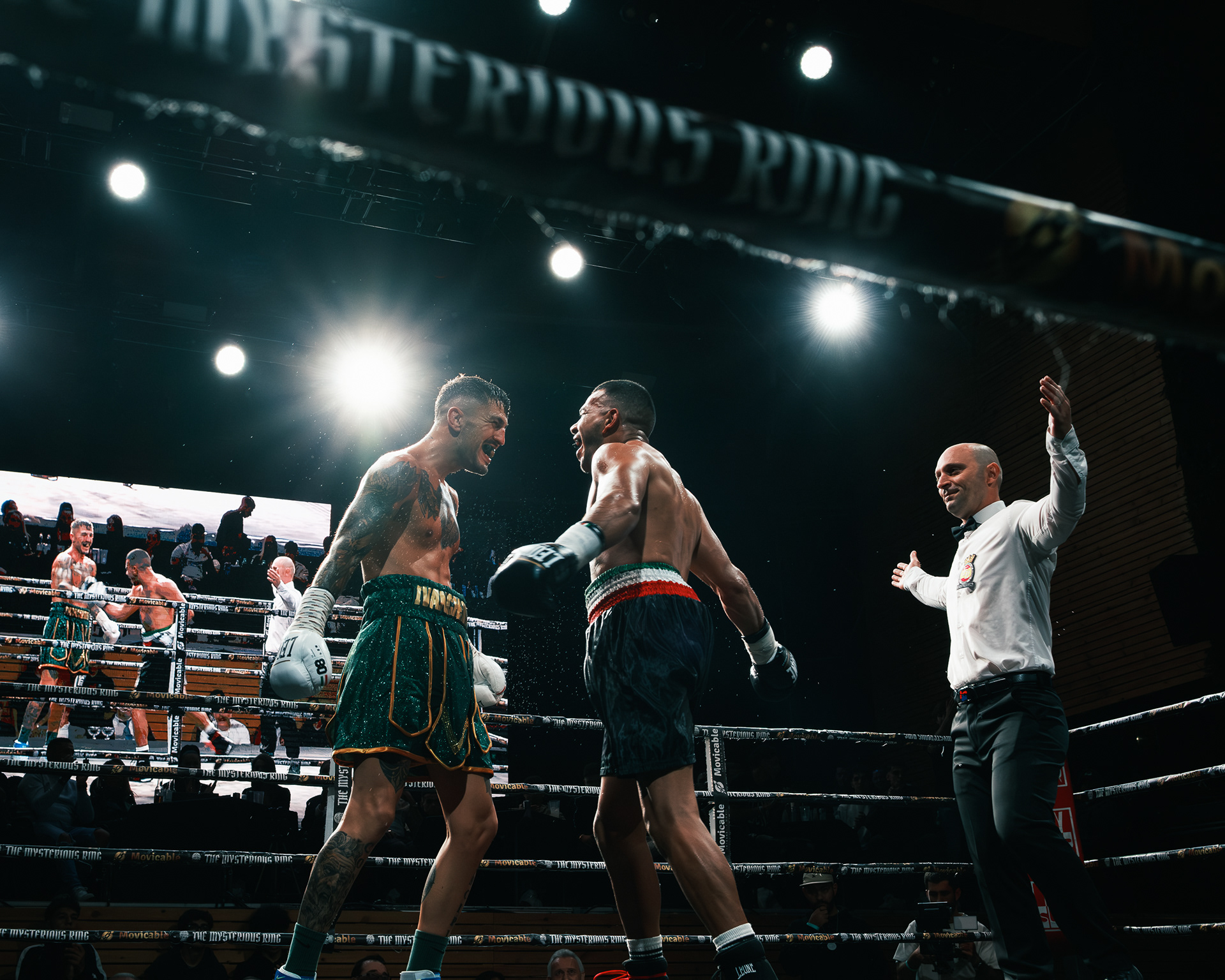 Dos boxeadores profesionales frente a frente al terminar el combate, con el árbitro levantando un brazo.