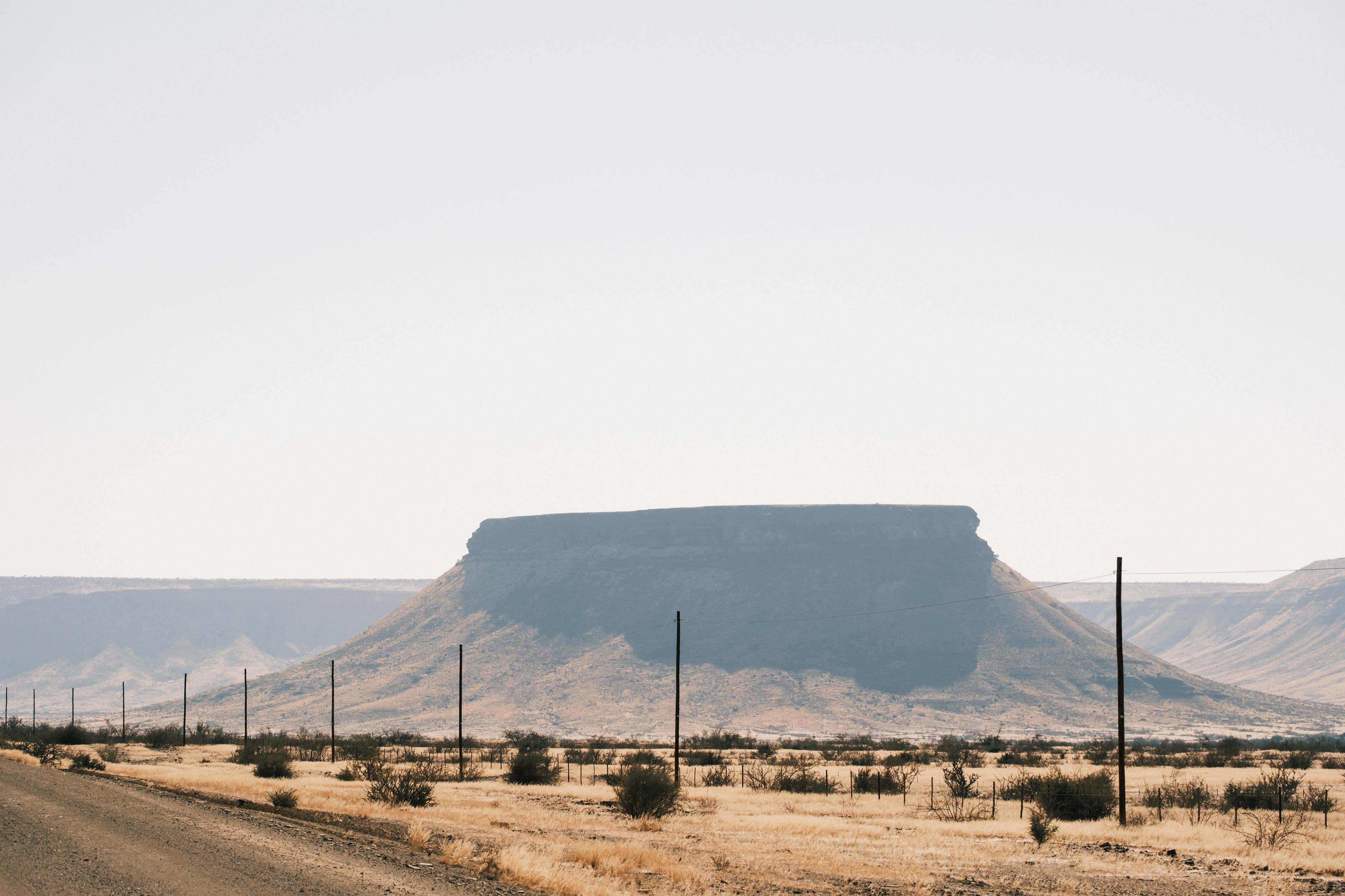 Montaña de cima plana junto a una carretera y una cerca en Namibia.