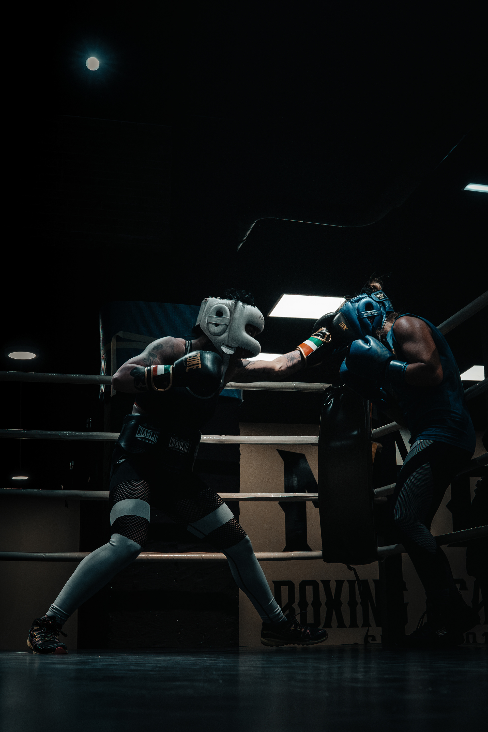 Boxeadora con casco blanco extendiendo un golpe hacia una rival con casco azul.
