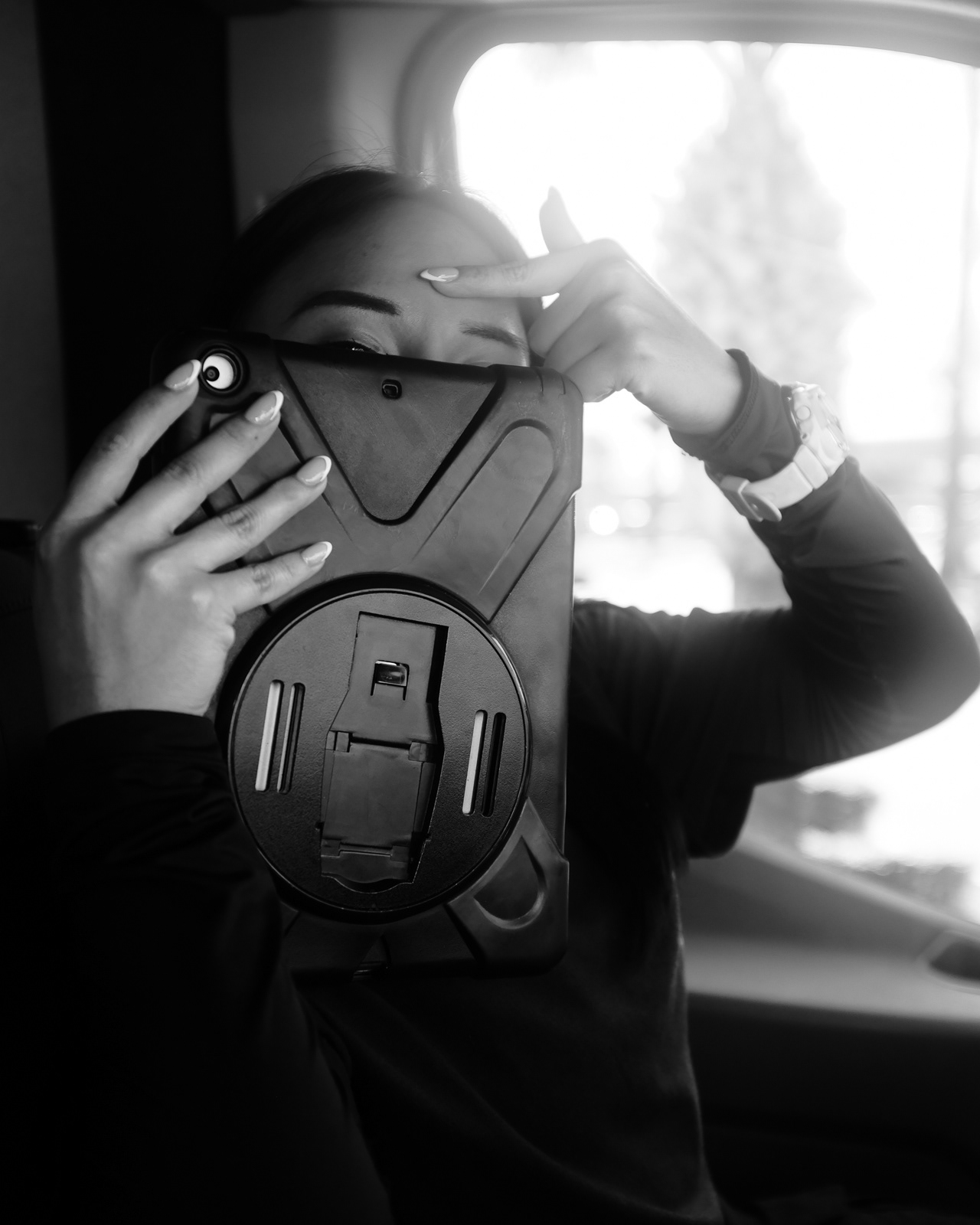 She hides behind the tablet and points at the marks the N95 mask left on her face.