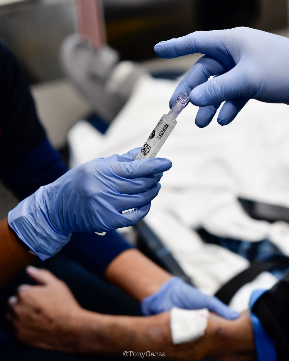 The Spark of Knowledge: Guided by seasoned paramedics, new medics learn emergency care as they enter and work in the field—a full-circle moment every medic experiences. Such mentorship is both a professional and ethical duty—essential and sacred. Its purpose is to pass knowledge from one generation to the next so the profession can advance, the highest standards of care are maintained, life is protected, and, above all, harm is avoided. All of this is possible only if the new generation understands and carries these principles forward. In this moment, the seasoned medic hands a filled NS syringe to the trainee, guiding them to complete the IV procedure—a spark of knowledge that creates a spark of life for the patient.