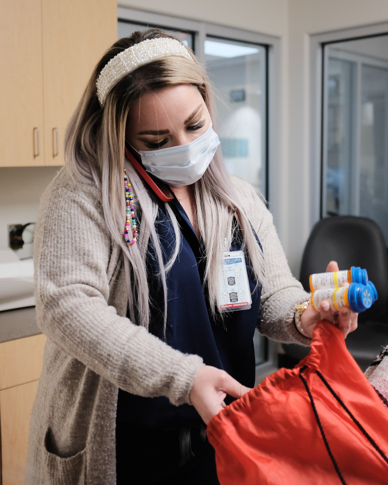 R. Aguirre, Nurse Practitioner, with 11 years of service in the hospital. Here, she checks a patient’s medication to get their medical history while simultaneously, continuing treatment plan for another patient over the phone.