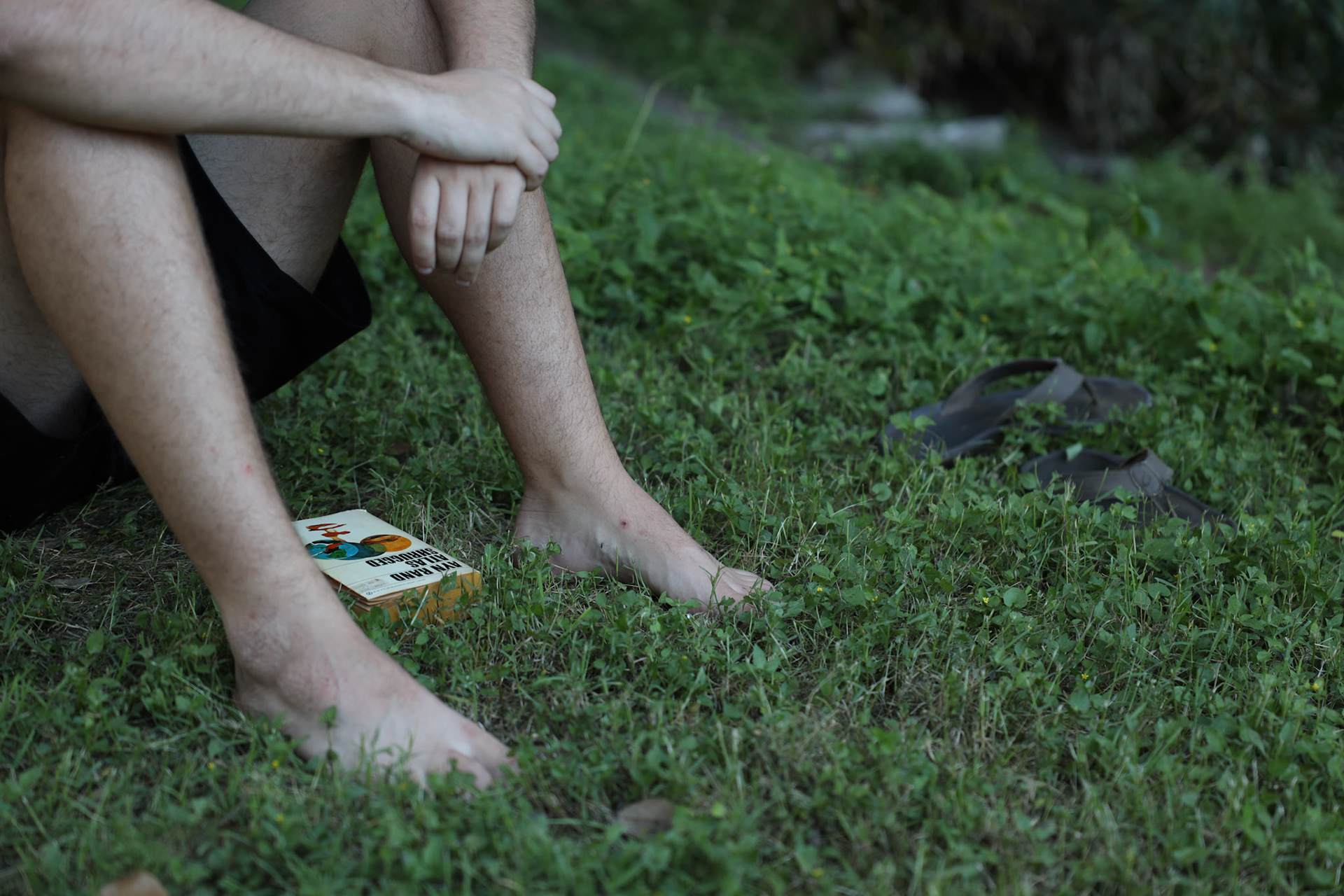 Gage Olfers reads his book among an empty park at the turtle pond at The University of Texas at Austin.
