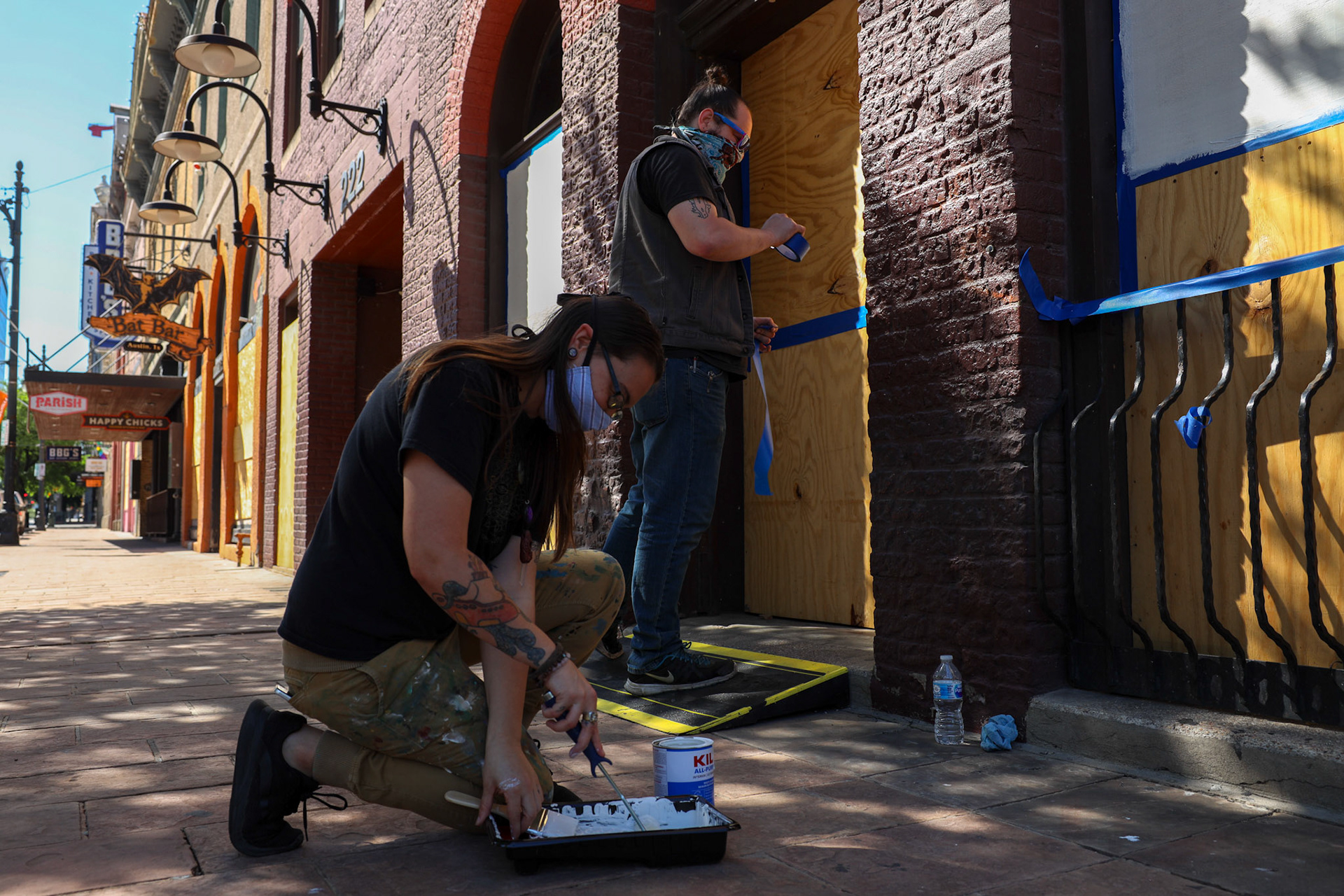 Janet McKeller and Joseph Darville apply primer to the plywood in front of the closed Recess game bar on April 14, 2020. McKeller and Darville planned to add their own mural, as art work began to show up on Sixth Street in Austin, TX.