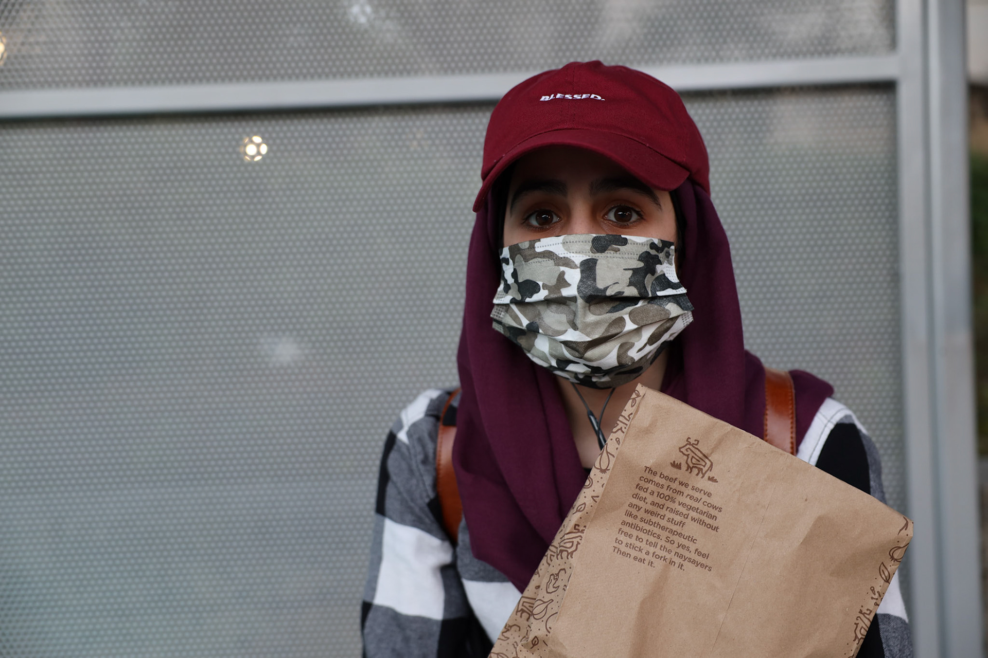 Zahra Ae waits at the bus stop after picking up take-out dinner on April 19, 2020 before Ramadan starts. Ae currently works at an insurance company and is the only one in the office during the shutdown.