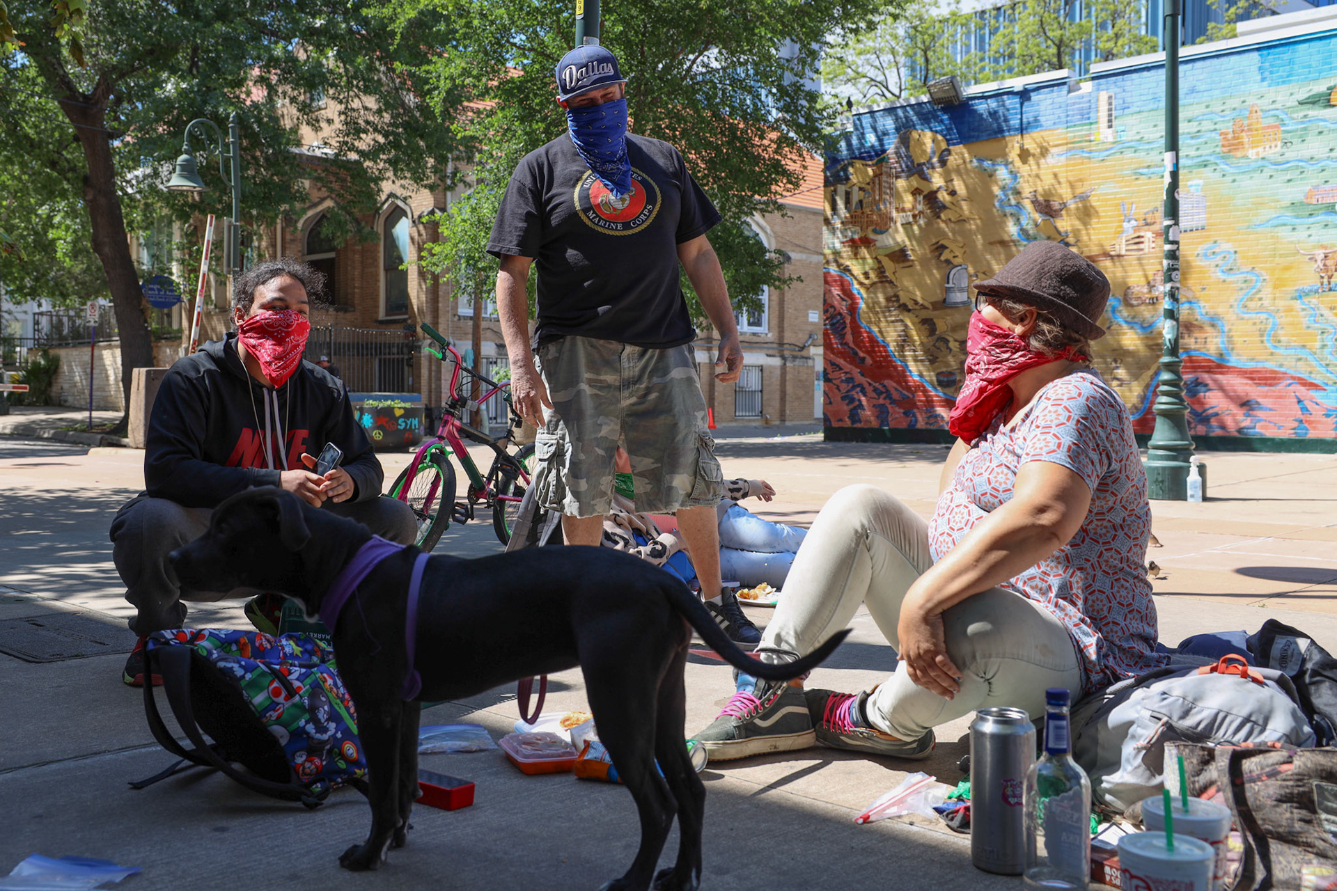 Johnny (left), Fatboy (middle), and Chrissy sit within the Guadalupe Street art district on April 14, 2020. The three and other displaced Austinites set up to drink and eat after receiving their stimulus check payments from the Coronavirus pandemic.