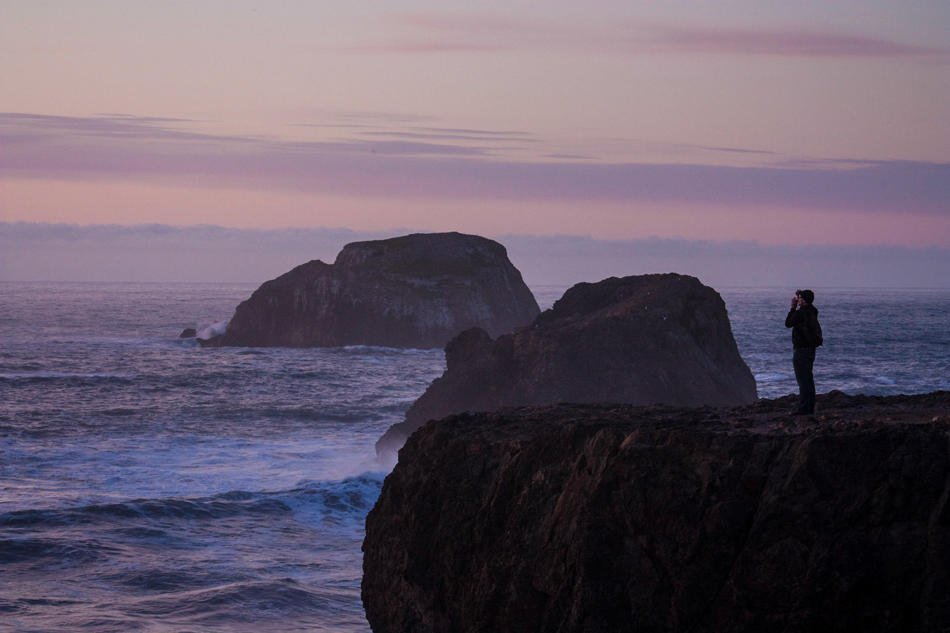 A man photographs the sunset on the coast of Trinidad, CA.