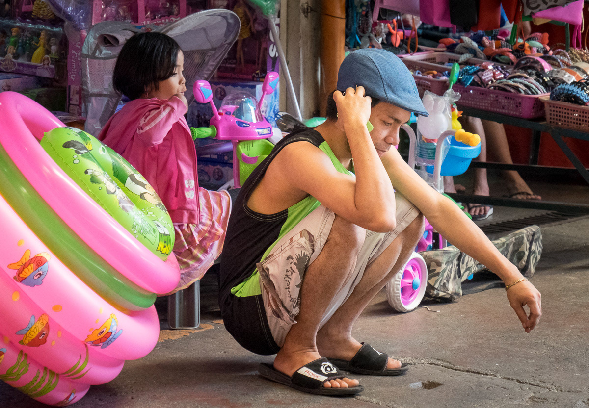 Man crouching with his cell phone, Marikina Markets, Philippines, 2015