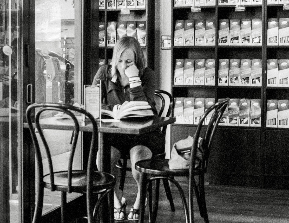 Woman reading book at a table in Ten O'clock Cookie cafe, Masterton, 2016