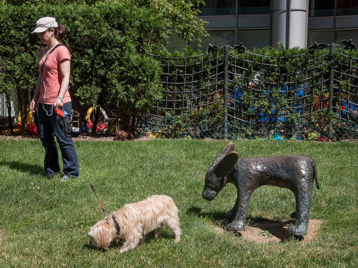 Woman with a dog in front of a dog statue, Downtown Toronto, 2011