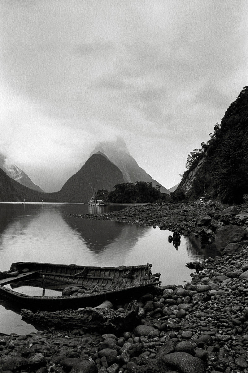 Rotting boat on shore of Milford Sound with Mitre Peak beyond