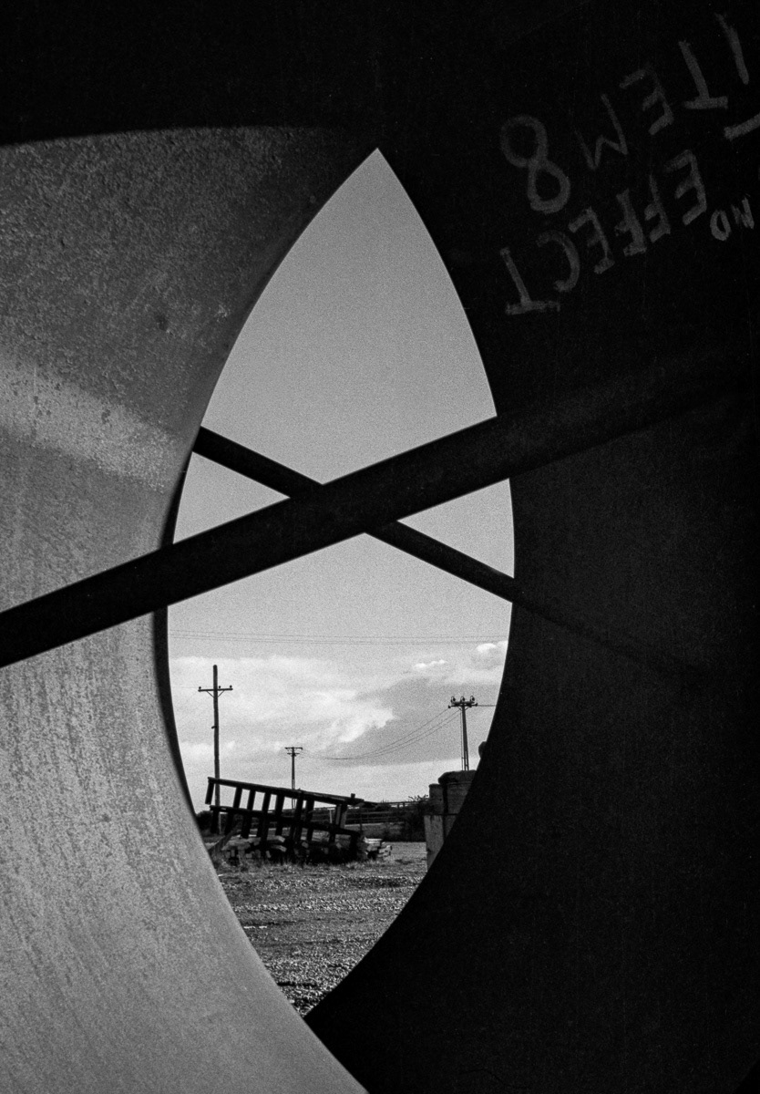 Poles and wires seen through pipes, Invercargill railway yards, Southland
