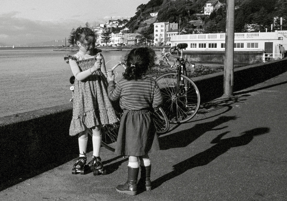 Two children with ice creams, one on roller skates, Oriental Parade, Wellington