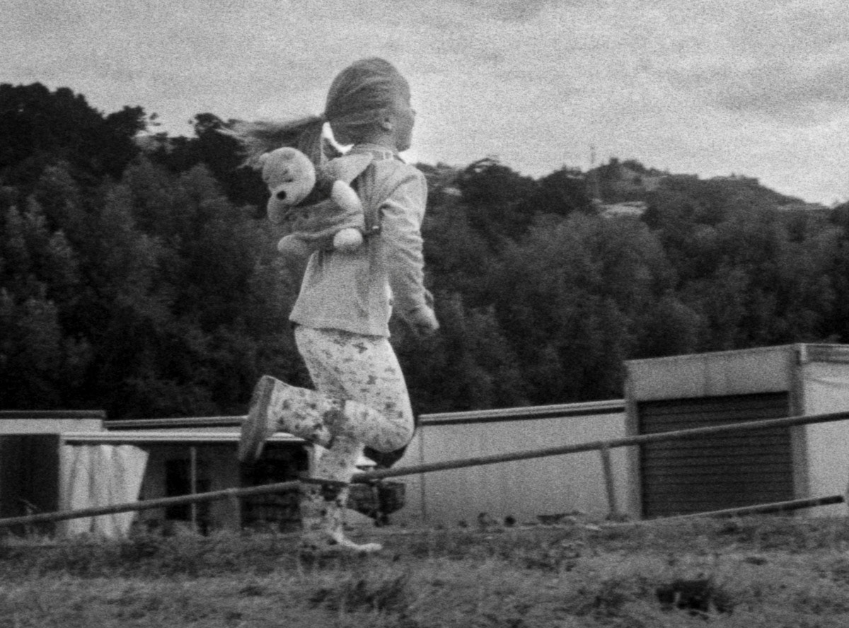 Girl with her teddy bear running beside the Riverbank market, Lower Hutt, 2016