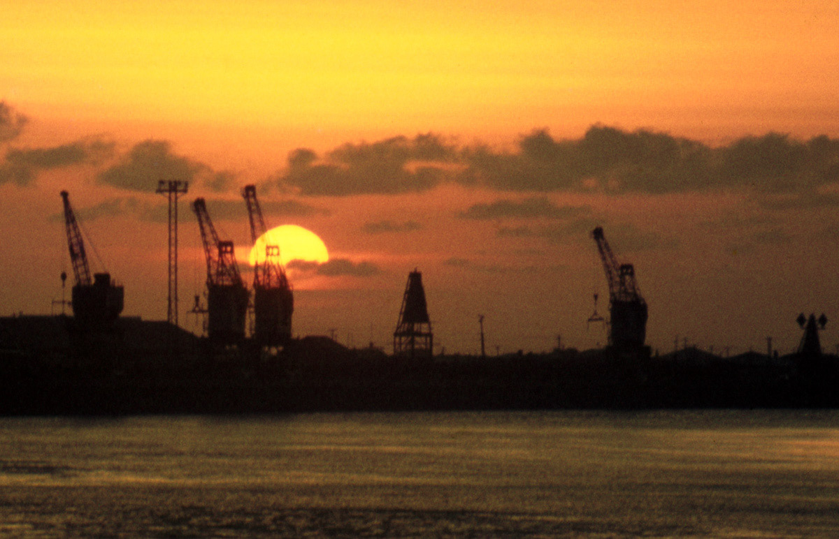 Sunset behind cranes for loading coal along the wharf at Greymouth