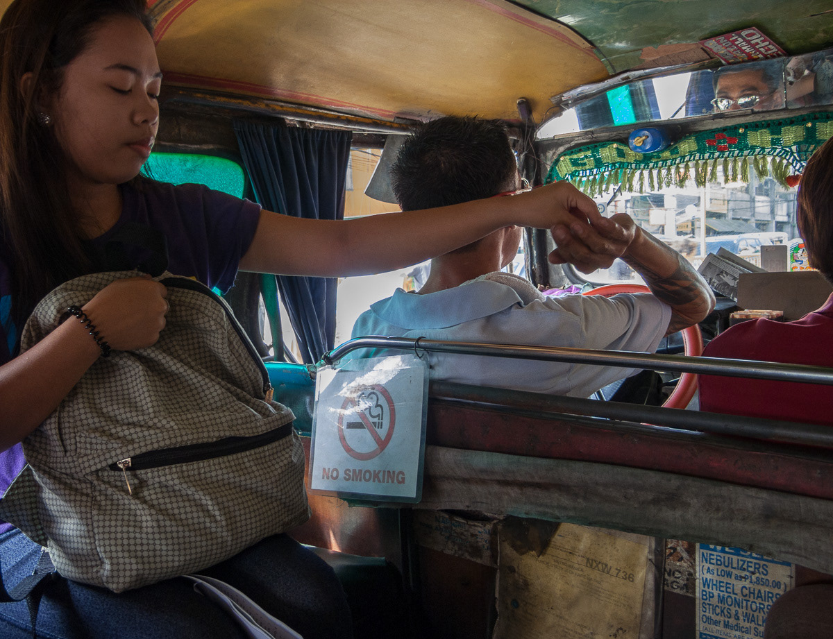 Passenger passing fare to the jeepney driver, Fare being paid, Marikina, Philippines, 2013