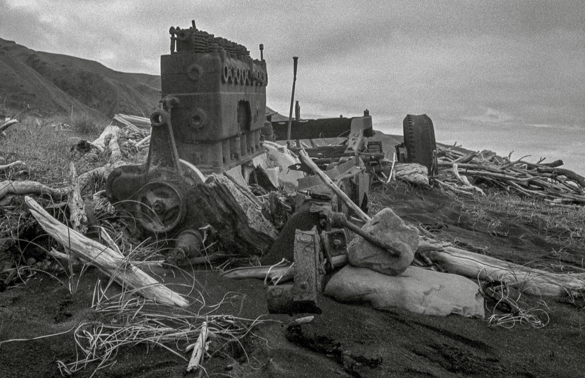 Old chases and engine lying in the sand beside the beach, South Wairarapa Coast, 1980