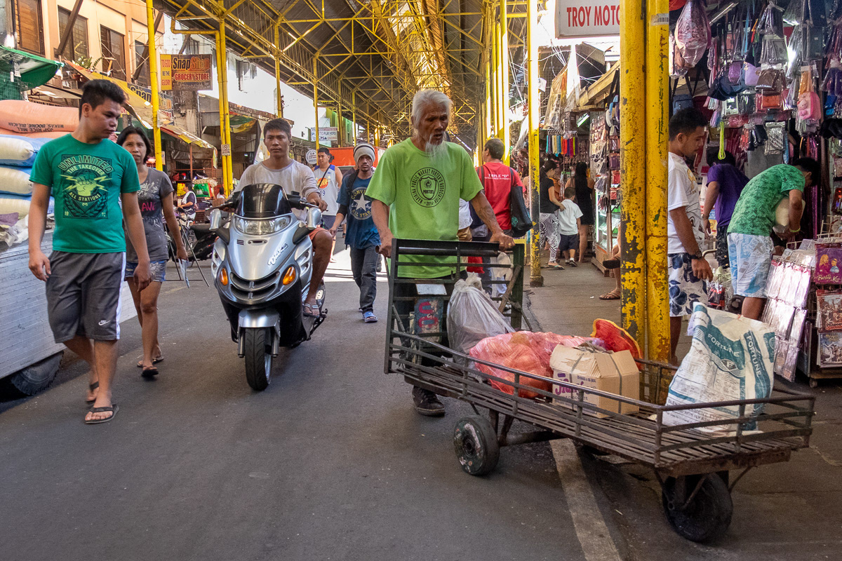 Man with food on trolley and passing motorcyclist, Marikina Public Markets, Philippines, 2015