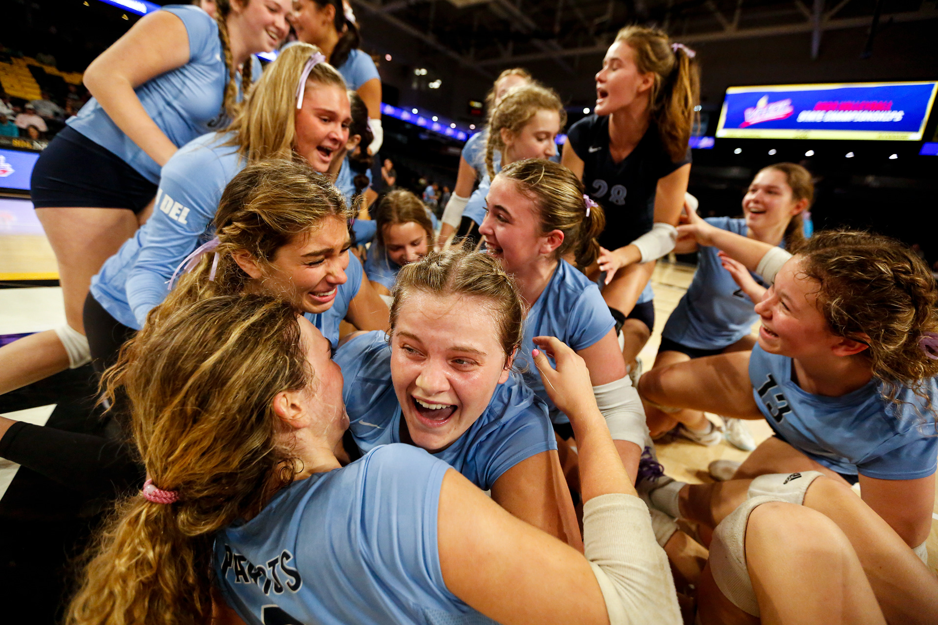 First Colonial players swarm their teammates on the court after defeating Riverside 3-1 in the Class 5 state championship at the Siegel Center on Nov. 17, 2023 in Richmond, Virginia.