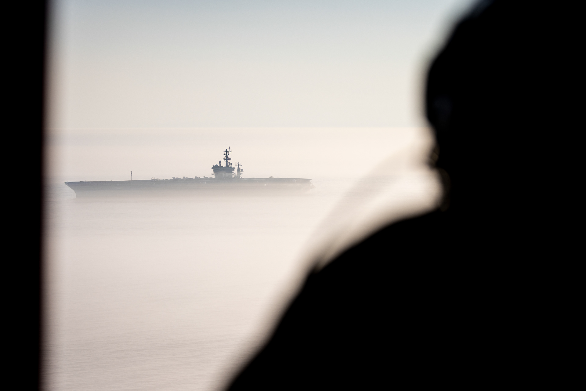 The USS Eisenhower (CVN-69) cuts through a layer of fog off the coast of Virginia as it heads home to Naval Station Norfolk, July 14, 2024, as seen from a navy helicopter.