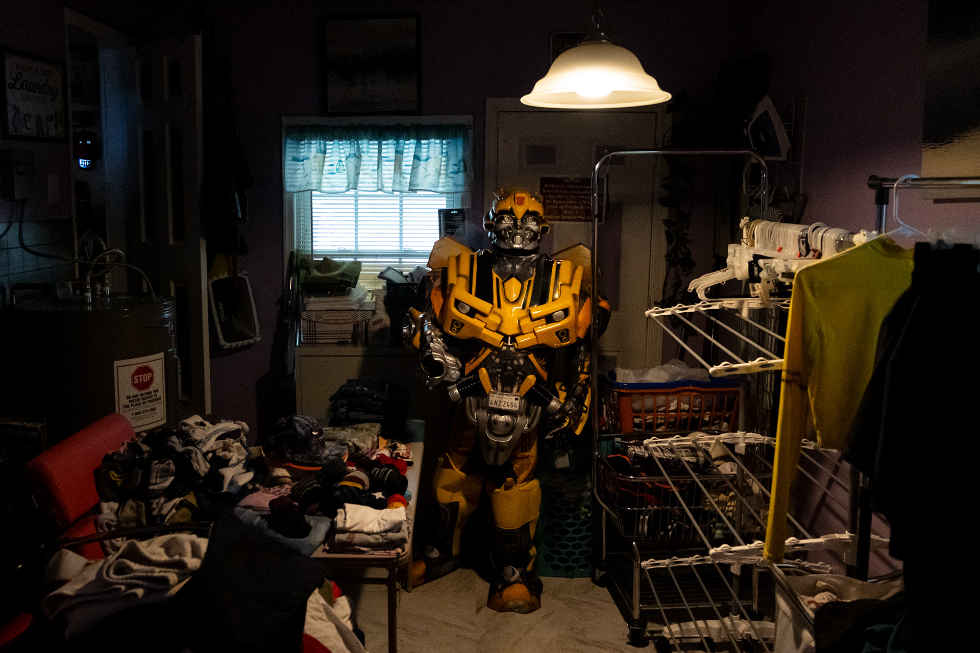 Aaron Jackson stands in the laundry room of his residence in Portsmouth, Virginia, dressed as Bumblebee from Transformers on June 23, 2023.  Jackson walks around three miles along Portsmouth Blvd waving to drivers hoping to bring them joy. He started wearing costumes to lift spirits during the coronavirus pandemic.