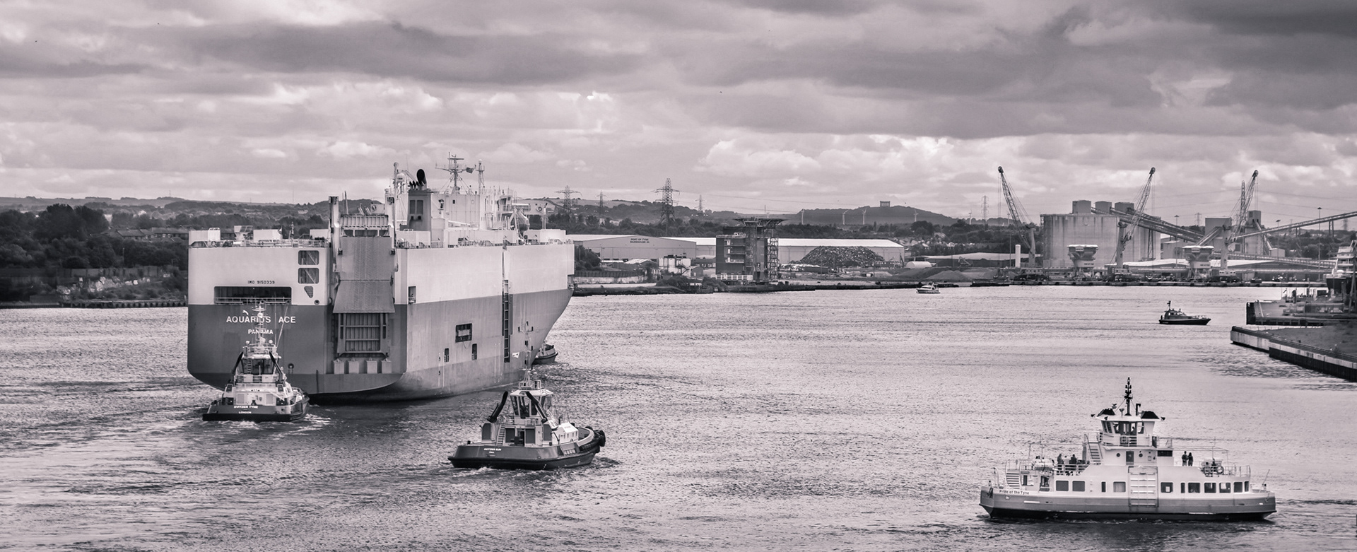 Nissan cargo ship with tug boats heading up river