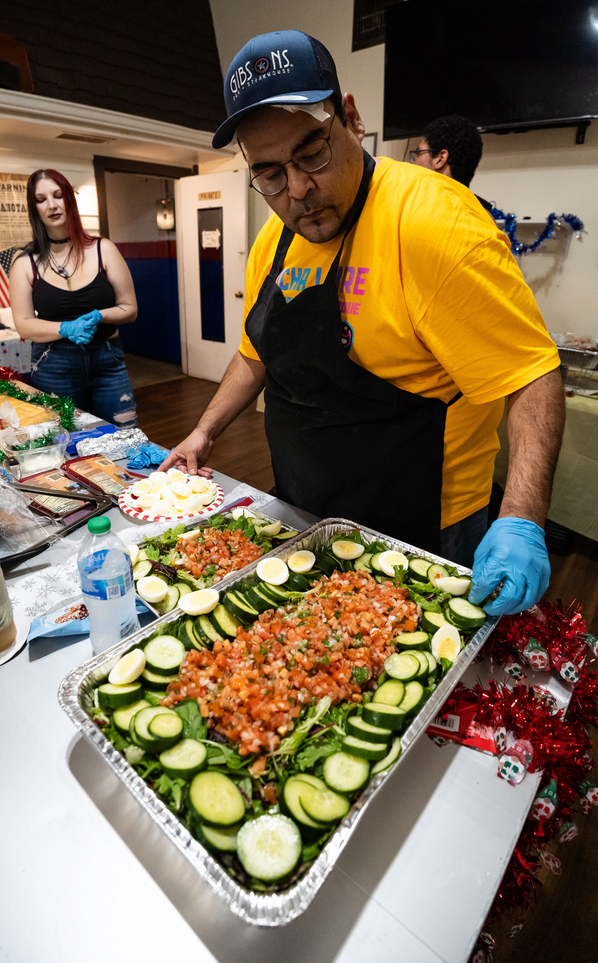 Daniel Cano prepara una bandeja de ensalada con su pico de gallo casero antes de una fiesta con temática navideña para Chicago Style Wrestling en el puesto 974 de la American Legion en Franklin Park, Illinois el 17 de noviembre, 2023.