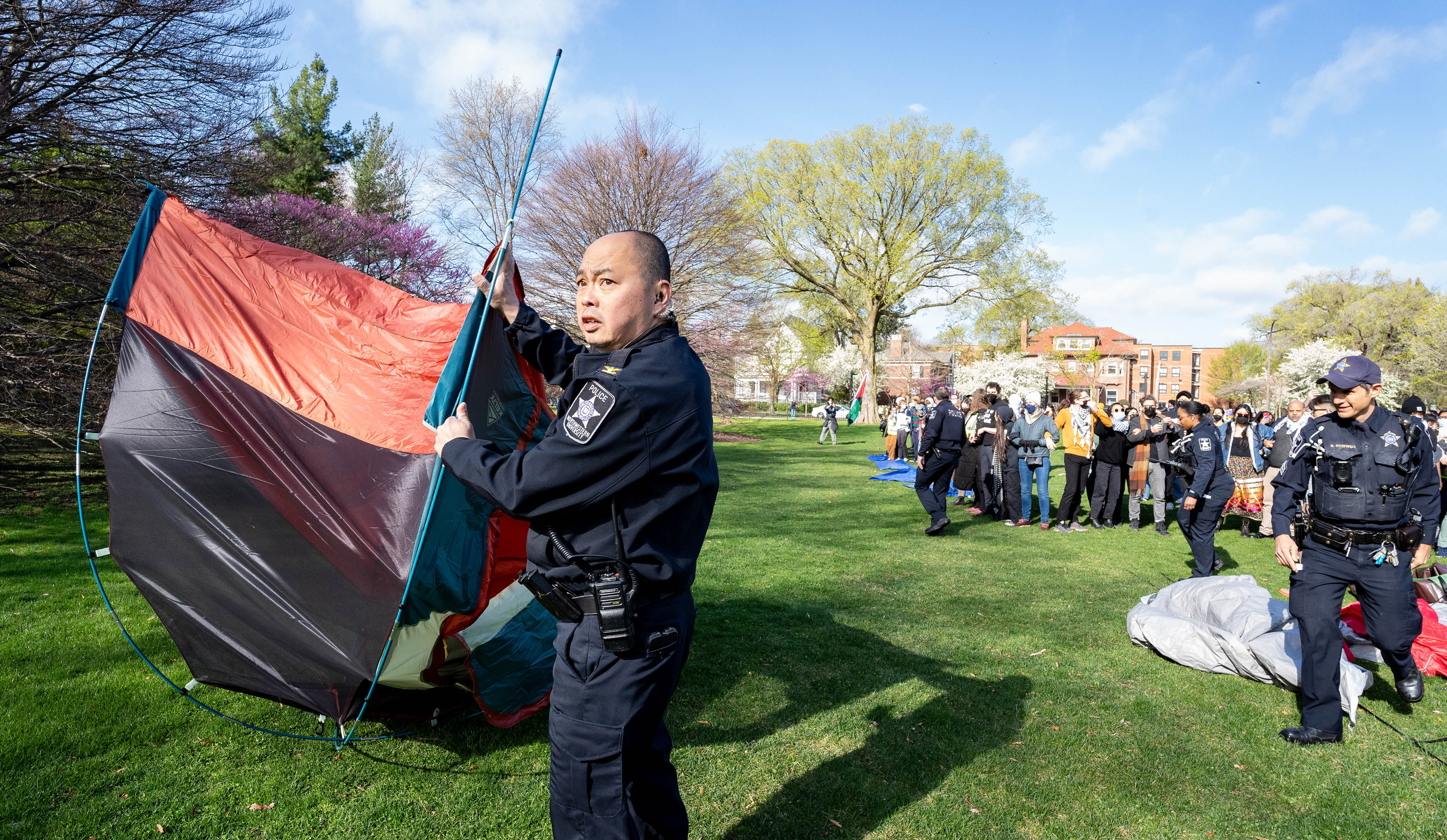 An Northwestern University police officer drags away a tent while pro-Palestinian students and faculty link arms to defend remaining tents within their recently-formed encampment at Deering Meadow in Evanston, Illinois on April 25, 2024. The TRiiBE