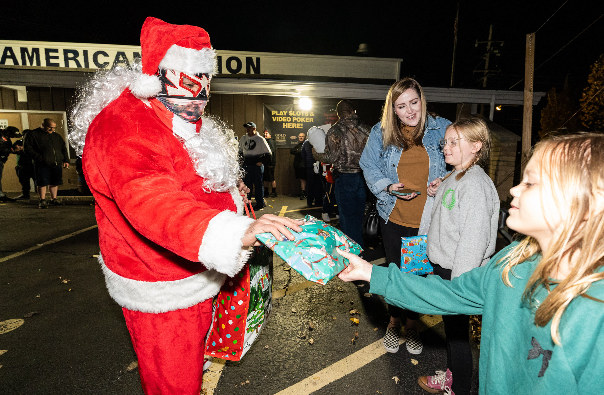 Daniel Cano, wearing his luchador mask and Santa Claus outfit, gives a present to Kallie Winters, 8, before a Chicago Style Wrestling show at the American Legion Post 974 in Franklin Park, Illinois on November 17, 2023.