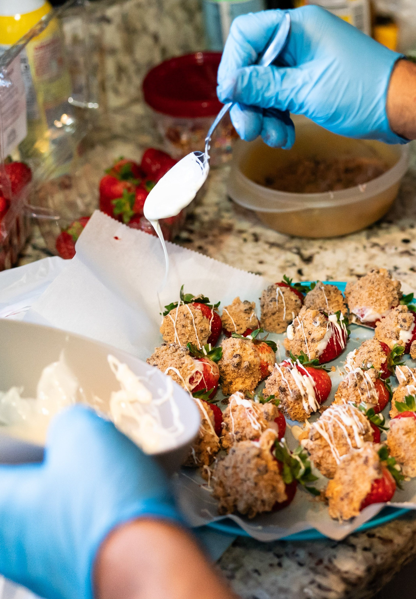 Daniel Cano salpica con chocolante blanco fundido fresas cubiertas en migajas de galletas en su casa en Westchester, Illinois el 17 de noviembre de 2023.