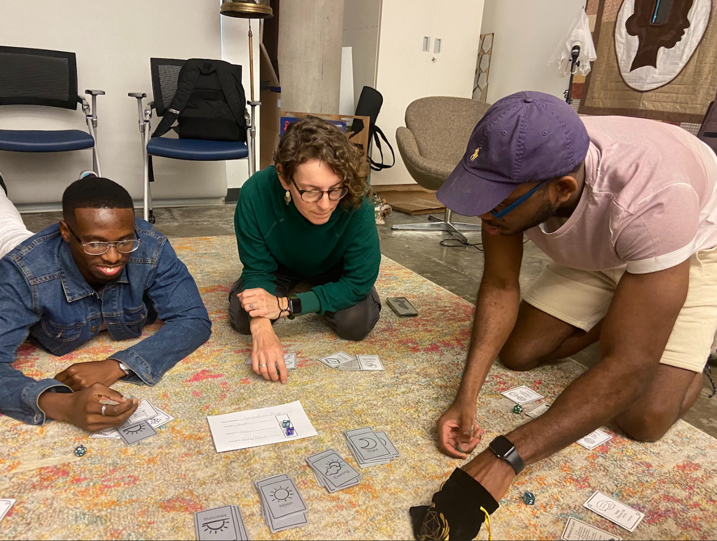 Three players sit on a rug and develop strategies to progress through the game.