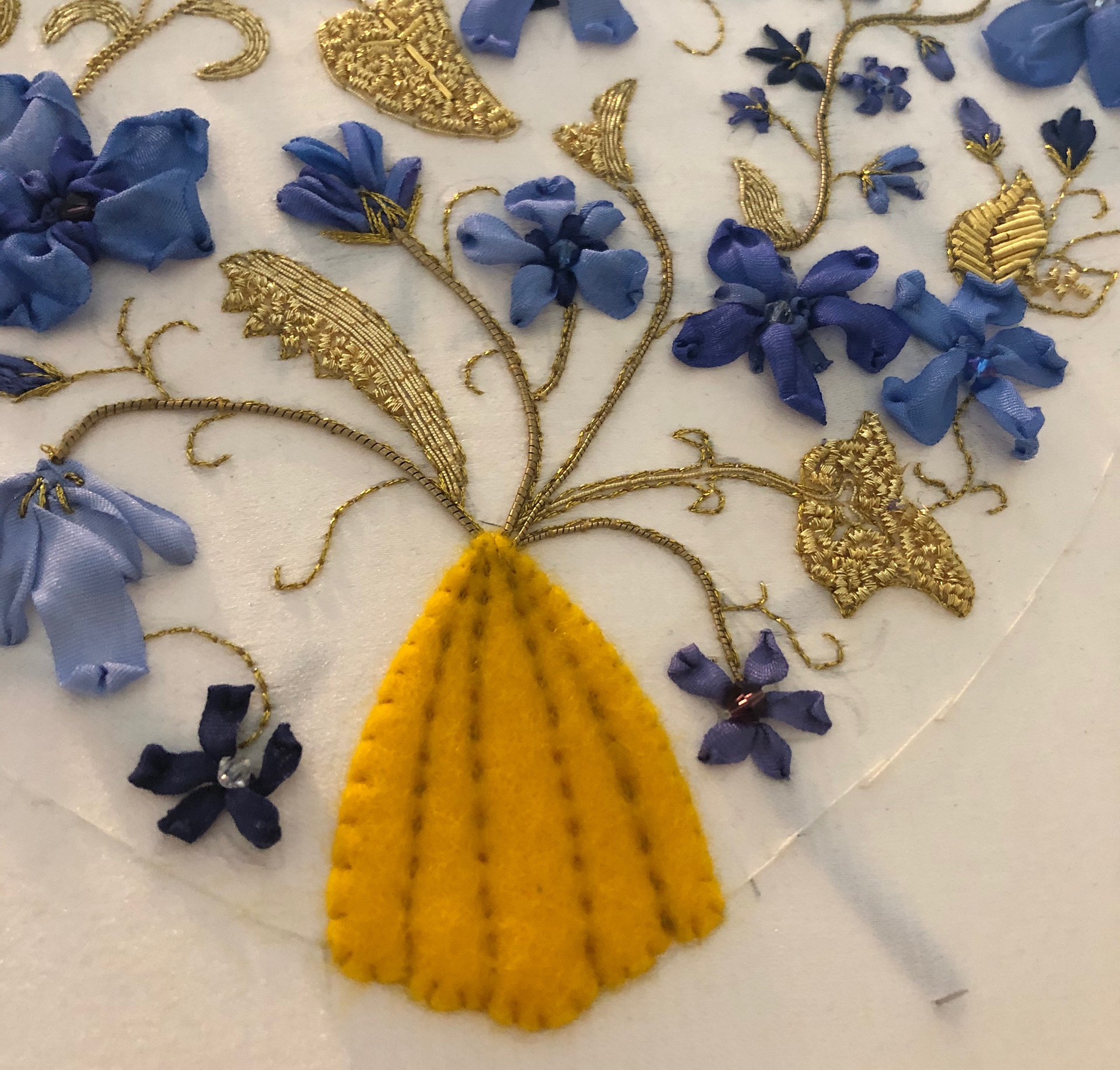 Felt padding is sewn down to create a solid base and dimension underneath the cutwork to be added.