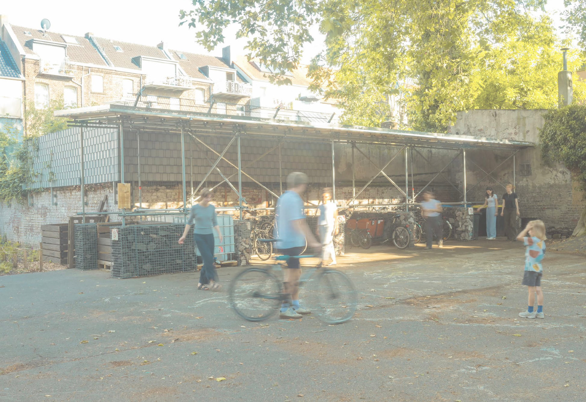 Pavillon Ehrenfeld nach Fertigstellung – Fahrradunterstand im Allerweltshof Köln-Ehrenfeld, Gerüststruktur mit Trapezdach im Betrieb, Besucher und Fahrräder im Vordergrund
