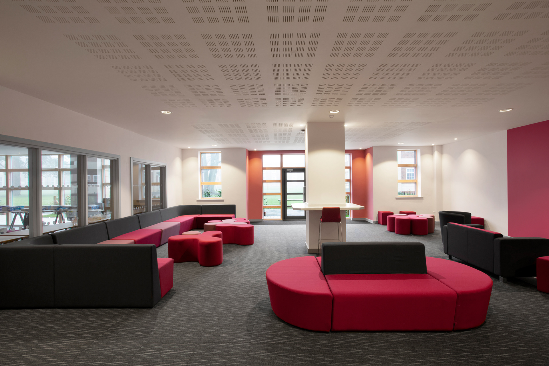Photograph of a common room lounge with pink and grey coloured furniture.