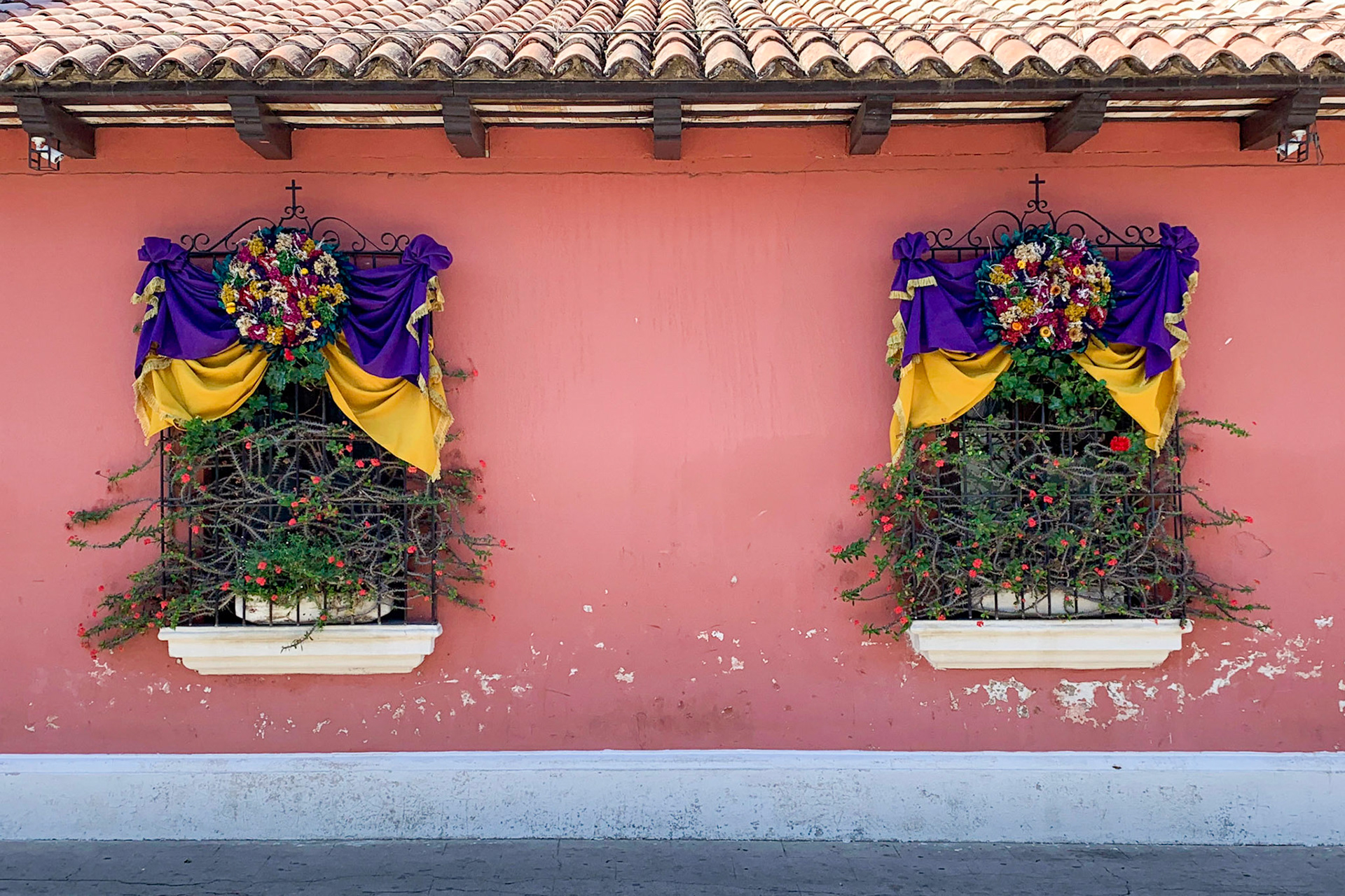 Two windows with flags and flowers in Antigua, Guatemala